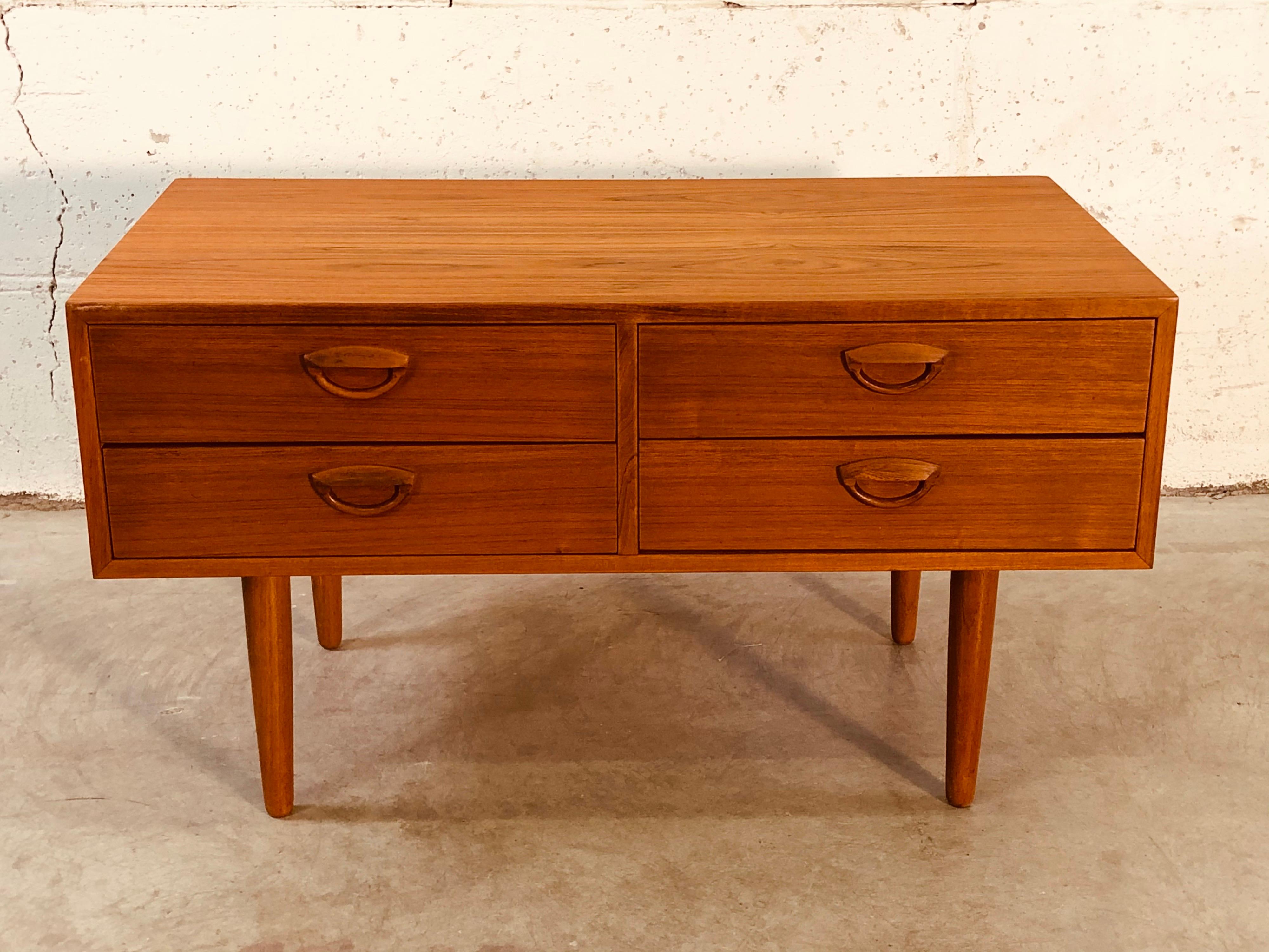 Vintage 1960s Danish teak four-drawer storage cabinet with round teak legs. The inside of the cabinet is a light birch wood. Recently refinished. No marks.