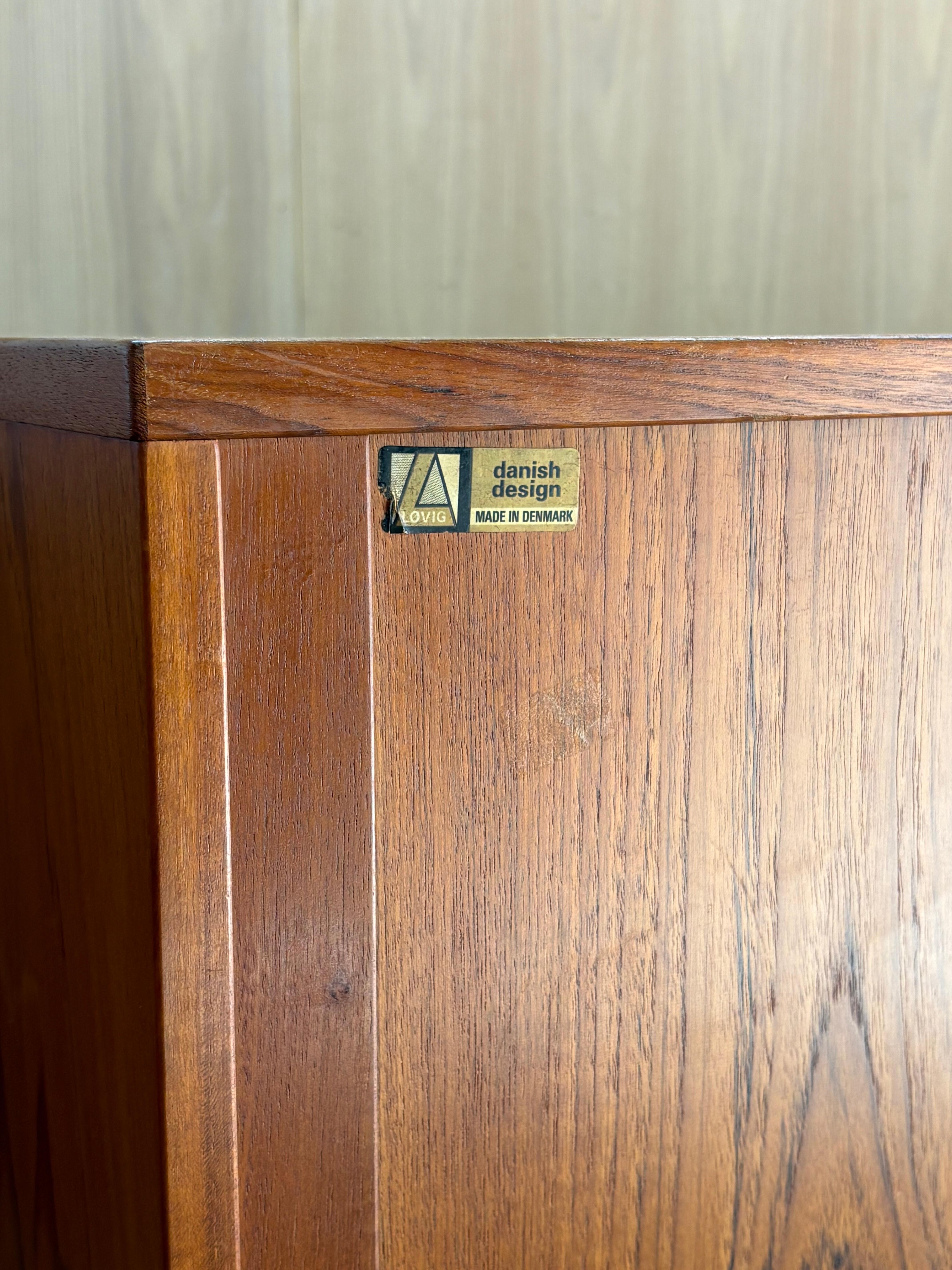 Excepcional ejemplo de diseño moderno danés, este armario de tambor de teca de los años 60, obra de Peter Lovig Nielsen, presenta puertas correderas lisas que ahorran espacio, estanterías totalmente ajustables y una parte trasera finamente acabada