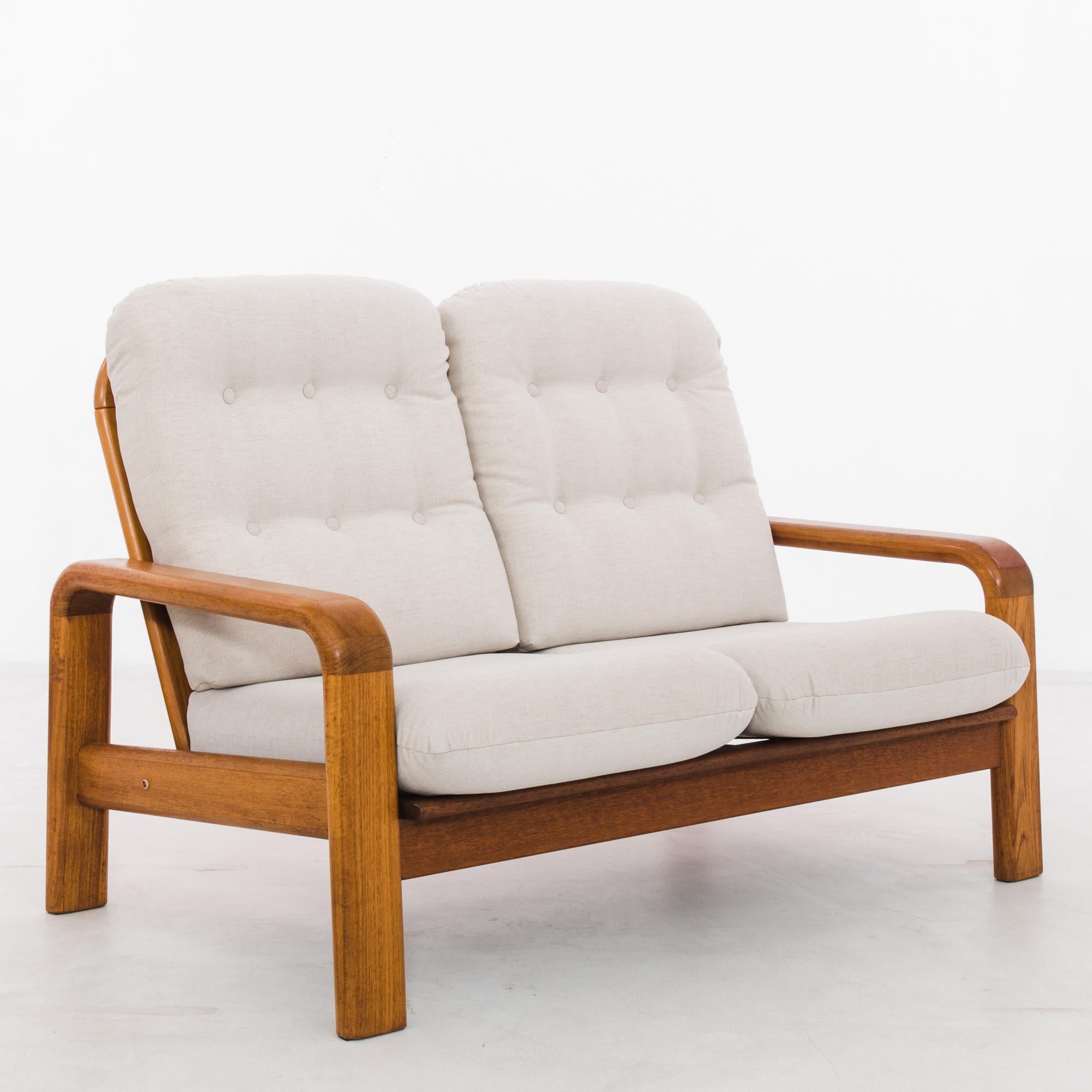 During the illustrious epoch of 1960s Danish design, this teak upholstered sofa emerged as a quintessential emblem of Scandinavian elegance. Fashioned from exquisite teak wood, the sofa's frame exudes warmth and richness, boasting a mesmerizing