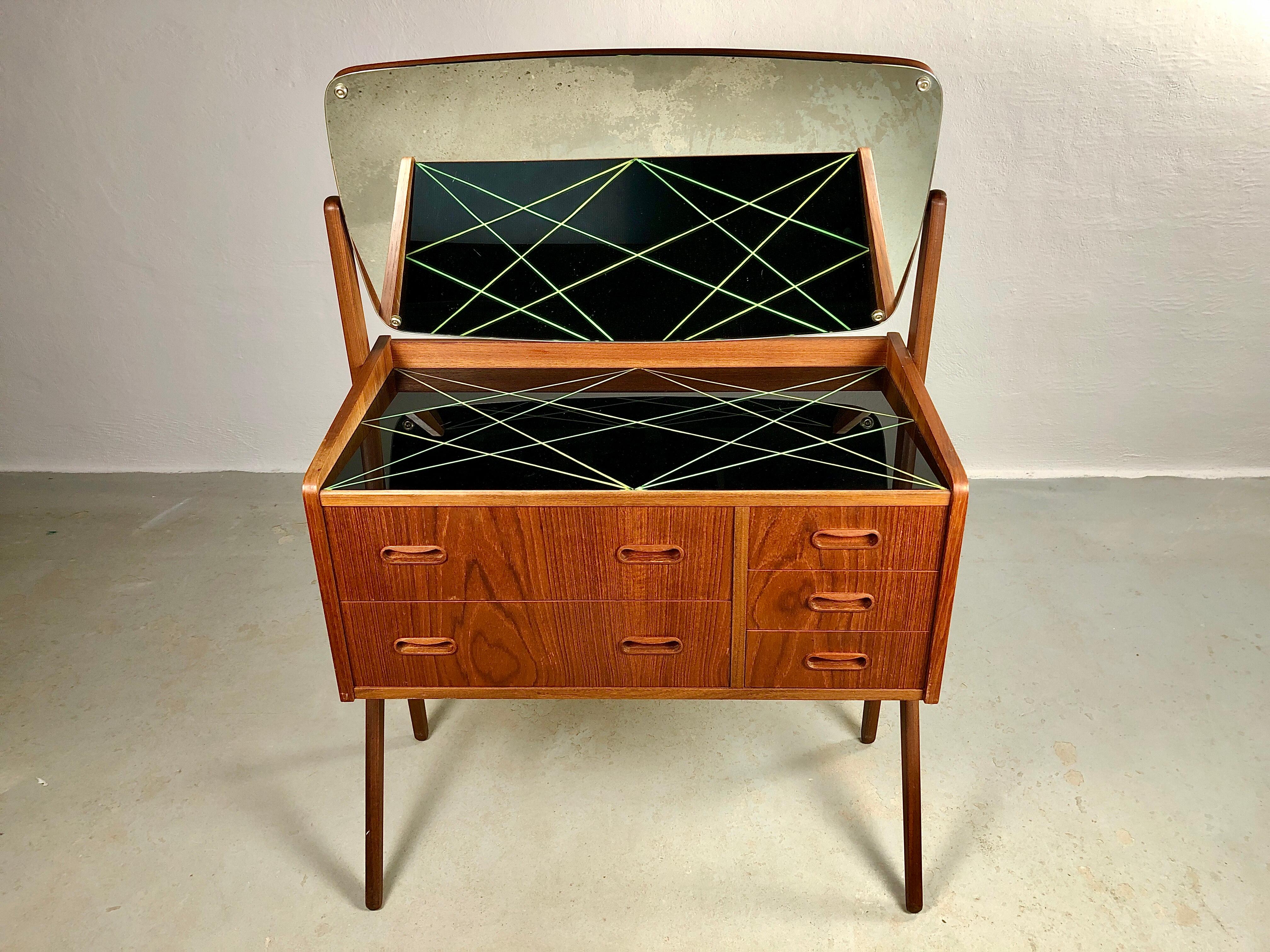 Danish teak dressing - vanity table from the 1960s.

The vanity table features a large adjustable mirror, an original black glass table top and 5 spacious drawers with room for what you need at the vanity table.

The table has been fully restored