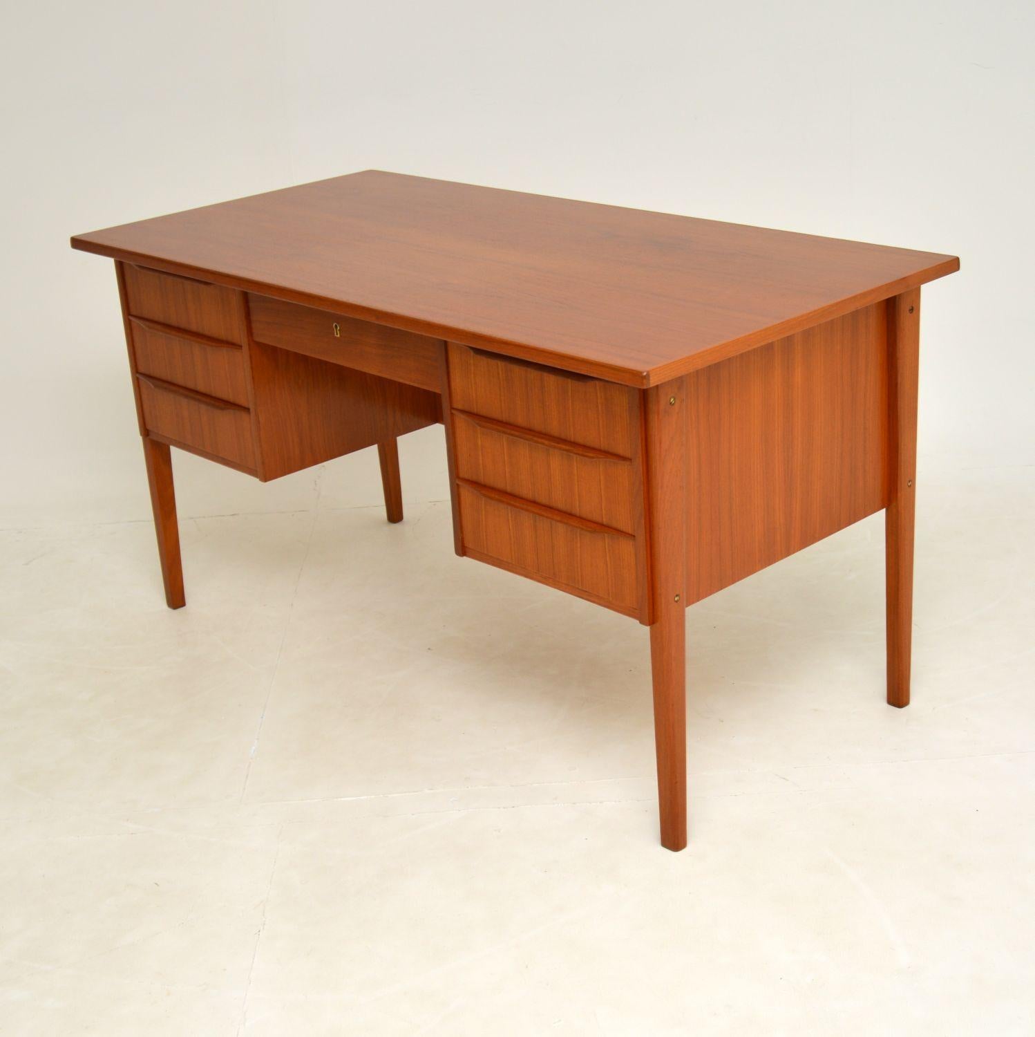 A stunning Danish teak desk of lovely proportions and style. This was made in Denmark in the 1960’s.

It is of amazing quality and beautifully designed. There are lipped handles on the drawers, lovely tapered legs and an open bookcase shelf on the