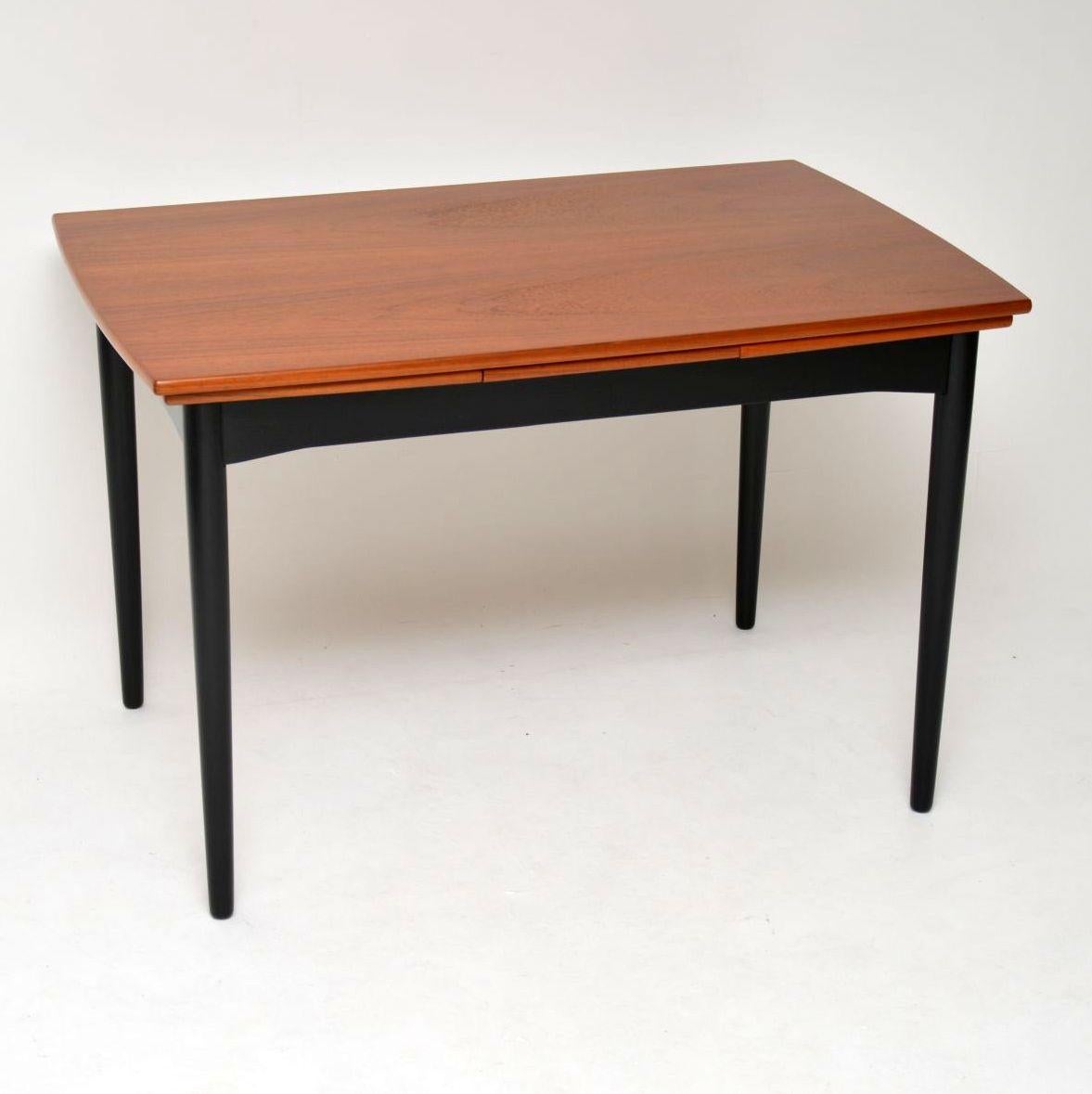 A beautiful and very well made vintage dining table made in Denmark, dating from the 1960s. It has a gorgeous teak top with two slides out leaves to extend the surface. The base is ebonised and the legs can be removed for ease of transport. We have