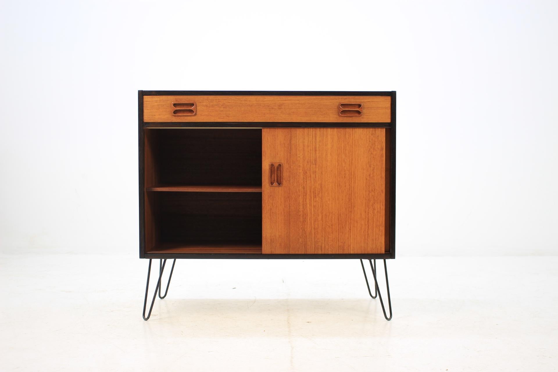 This cabinet features two doors with inner shelve and one drawer. The iron legs were added afterwards. This item was carefully restored. The wood of the body was stained to black.