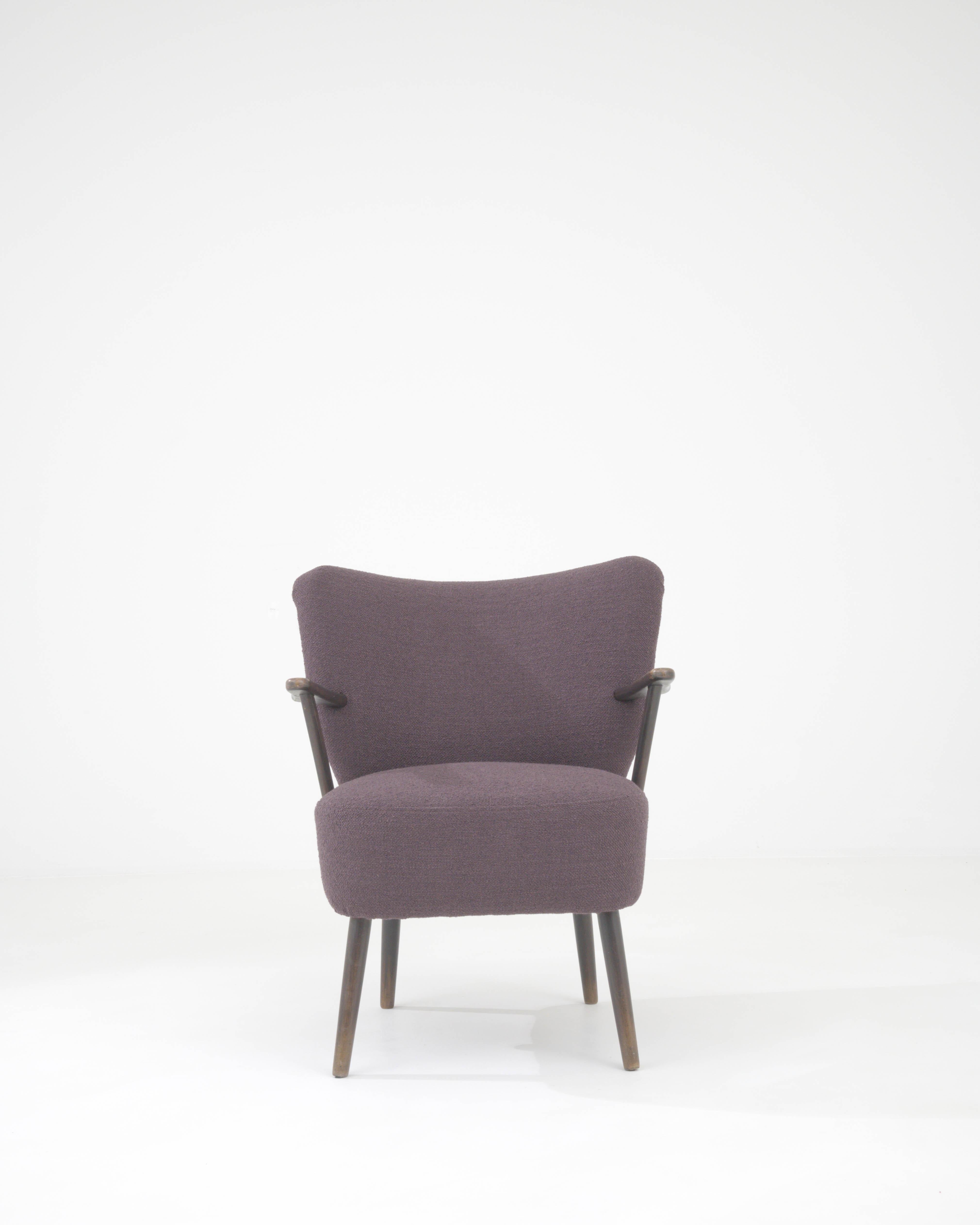 Step into the realm of classic comfort with this 1960s Danish Upholstered Armchair, a timeless piece that exudes both elegance and coziness. The chair's rich plum upholstery invites you to sink into its soft embrace, perfect for unwinding after a