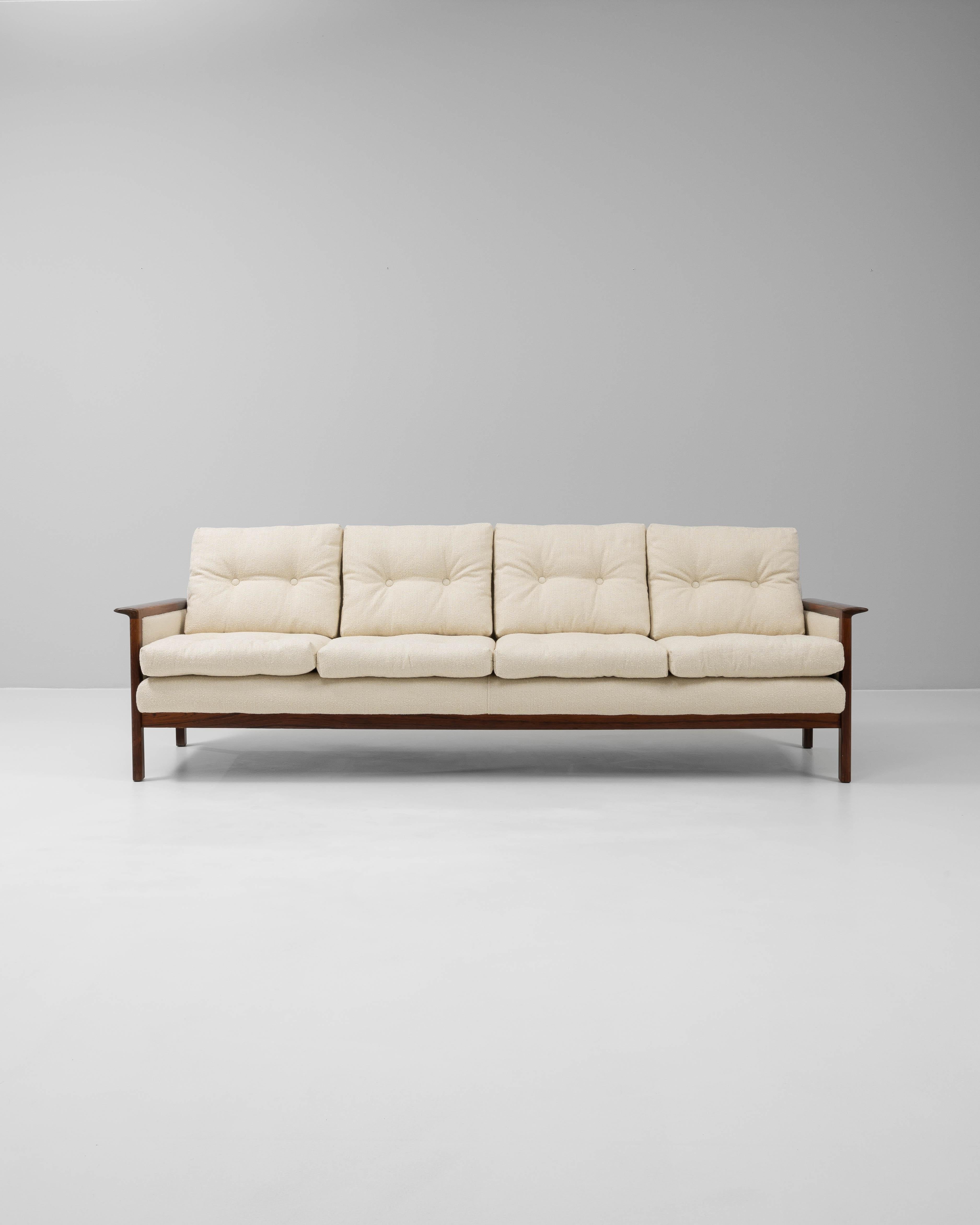 This 1960s Danish upholstered sofa by Hans Olsen is a refined example of Scandinavian modern design, combining elegant simplicity with exceptional craftsmanship. The rich walnut-stained frame features sleek lines and gently curved arms that