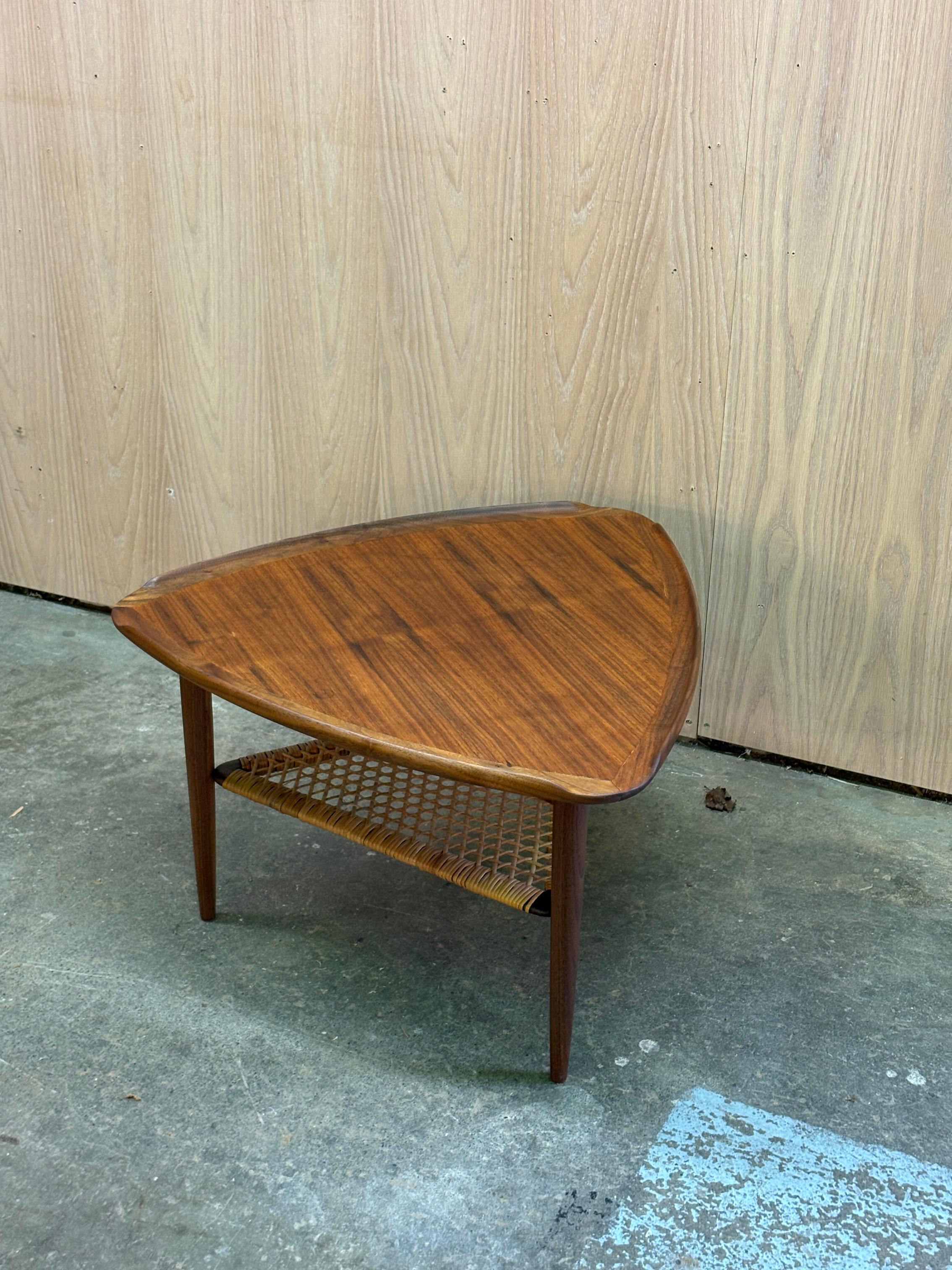 A beautifully sculpted 1960s Danish walnut coffee table showcasing the warm grain, organic lines, and thoughtful craftsmanship that defined the era. The triangular top features a gently raised lip, a functional and elegant detail that subtly frames