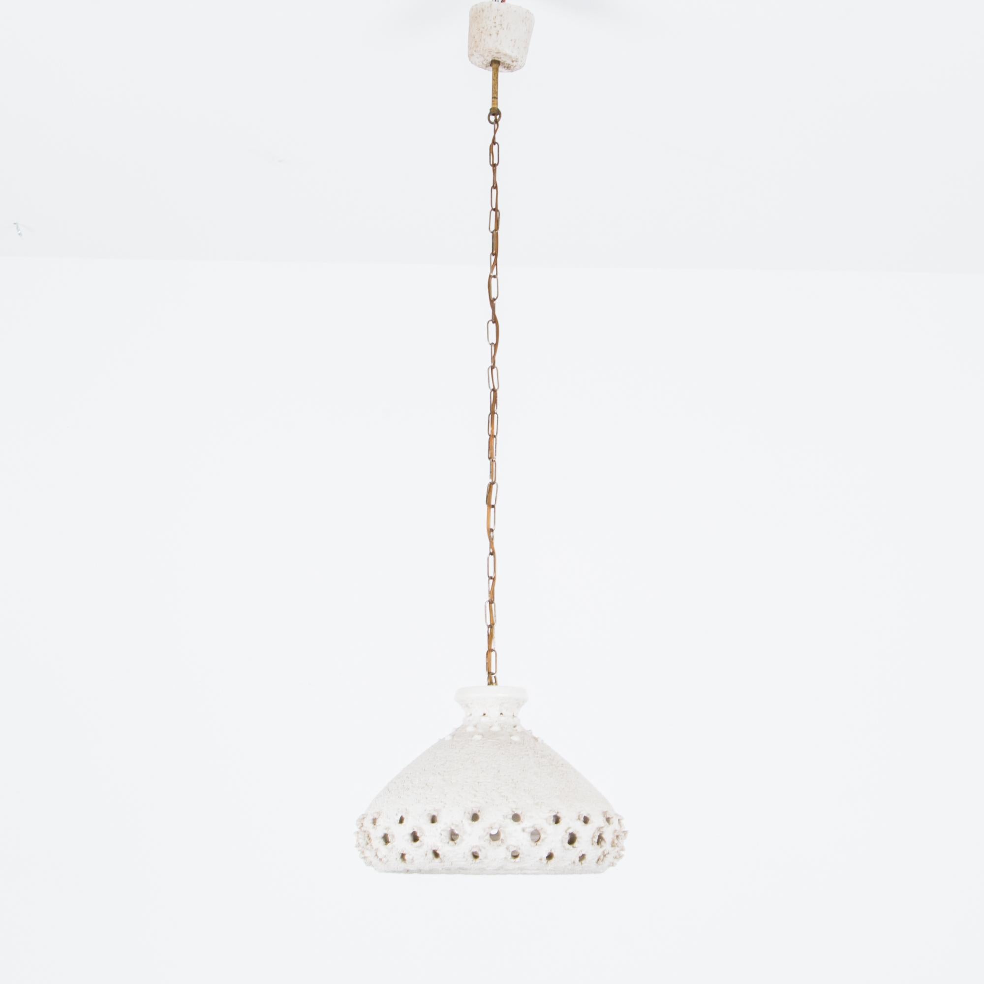 This pendant light was made in Denmark in the 1960s, and features a white ceramic light fixture suspended from a ceiling chain. The rough, unglazed texture of the ceramic fixture contrasts appealingly with its pretty, lace-like pattern, for an