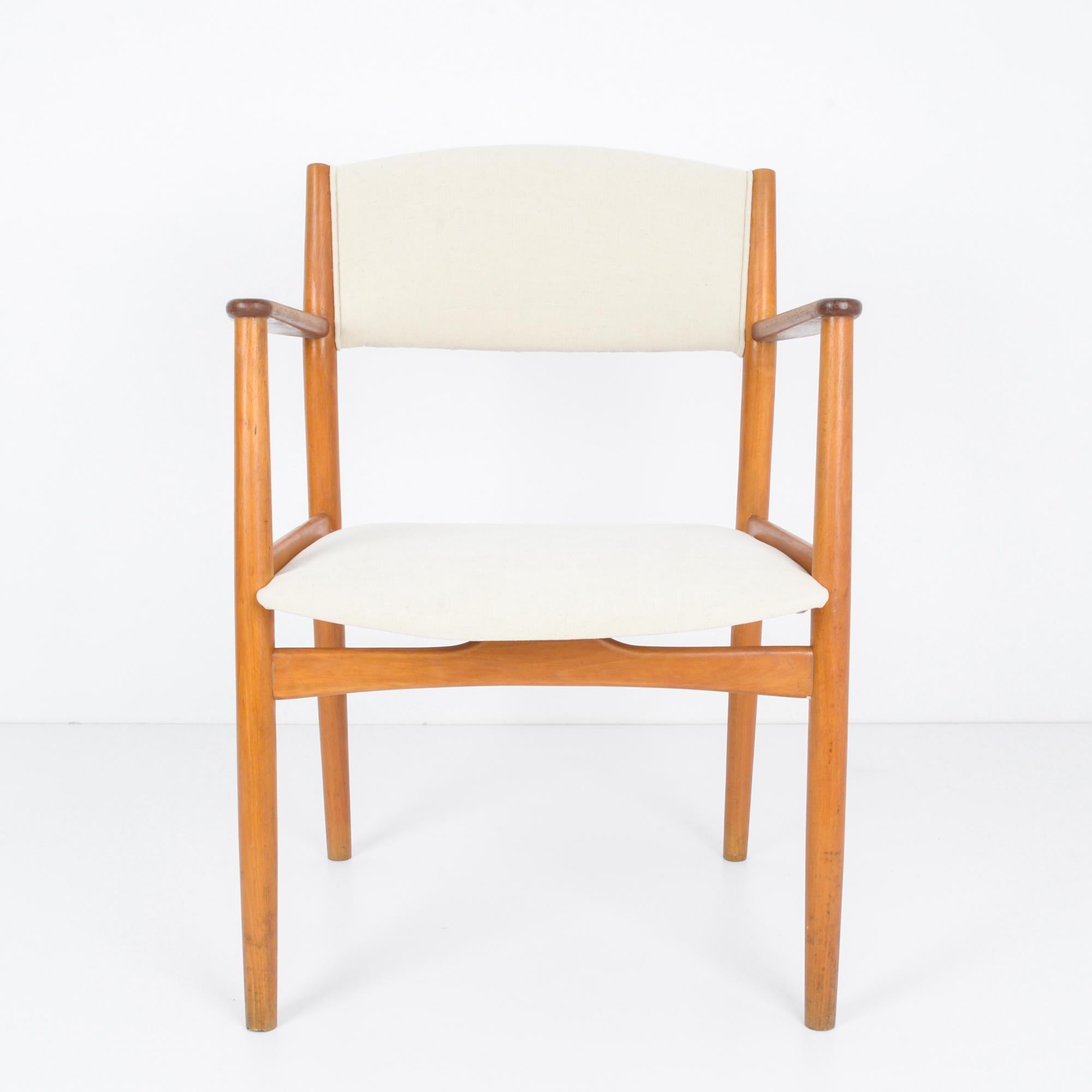 In the innovative design landscape of 1960s Denmark, this wooden armchair with an upholstered seat and back epitomizes the sleek sophistication and ergonomic comfort of the era. Crafted with meticulous attention to detail, this piece represents the