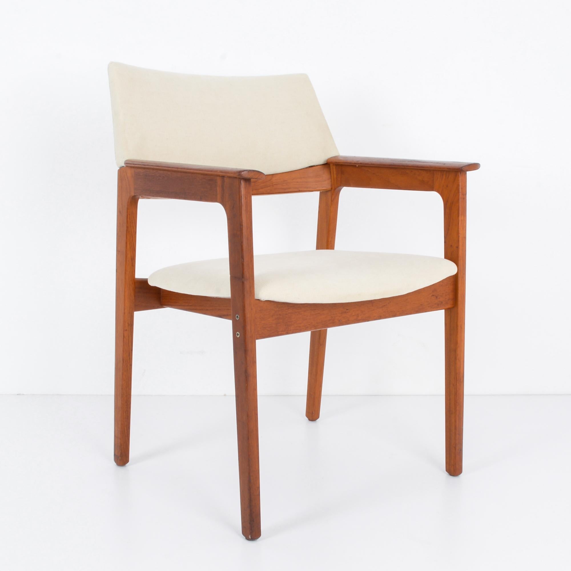 In the innovative design landscape of 1960s Denmark, this wooden armchair with an upholstered seat and back epitomizes the sleek sophistication and ergonomic comfort of the era. Crafted with meticulous attention to detail, this piece represents the