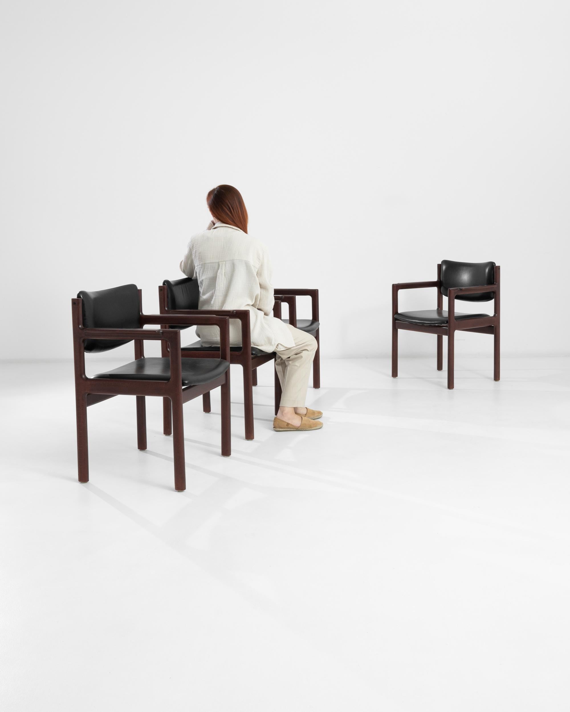 Los sillones daneses de madera de los años 60 con asiento y respaldo de piel desprenden un aire de elegancia clásica y confort refinado. Este conjunto de cuatro sillones presenta una rica estructura de madera oscura con reposabrazos bellamente