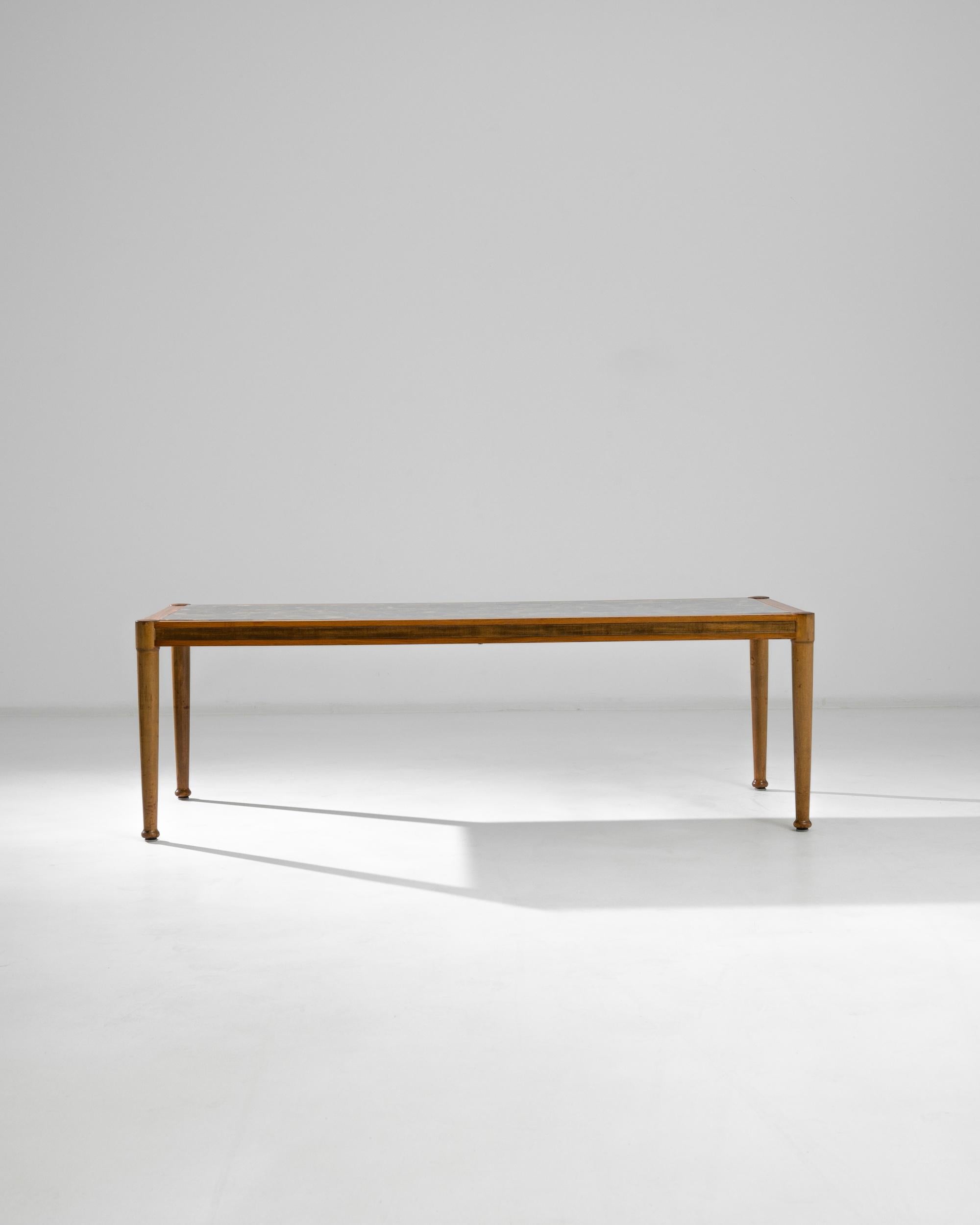 A wooden coffee table with an epoxy top from Denmark, produced circa 1960. The slim profile and clean lines on this low-slung coffee table give it a light, airy feeling, that belies the actual heft of the piece. The clear top allows light to freely