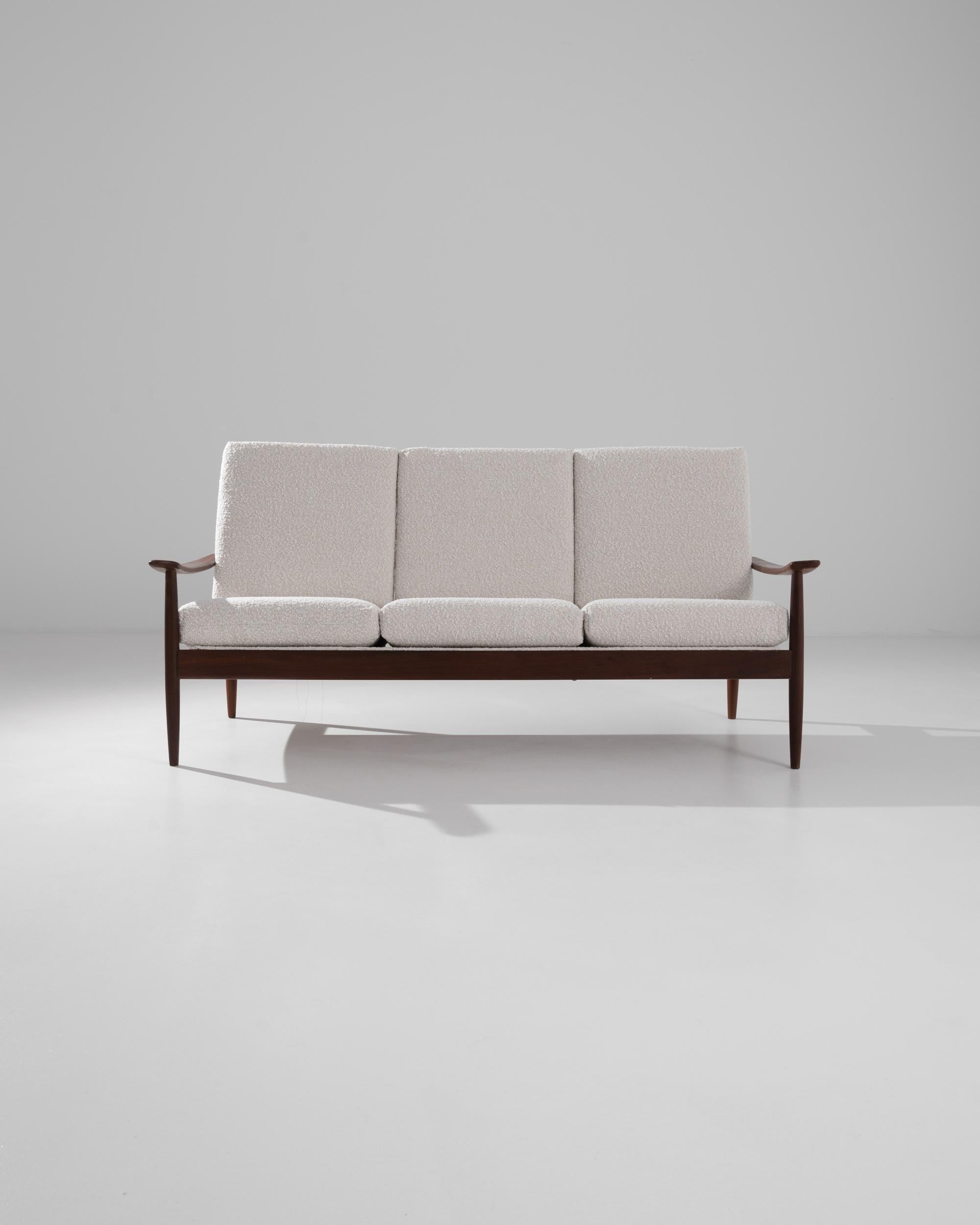 Light and elegant, this 1960s wooden sofa embodies the effortless simplicity of Danish Modern furniture. The silhouette is clean but graceful: slender spindle legs create a poised stance, while the fluid curve of the armrest gives a sense of motion