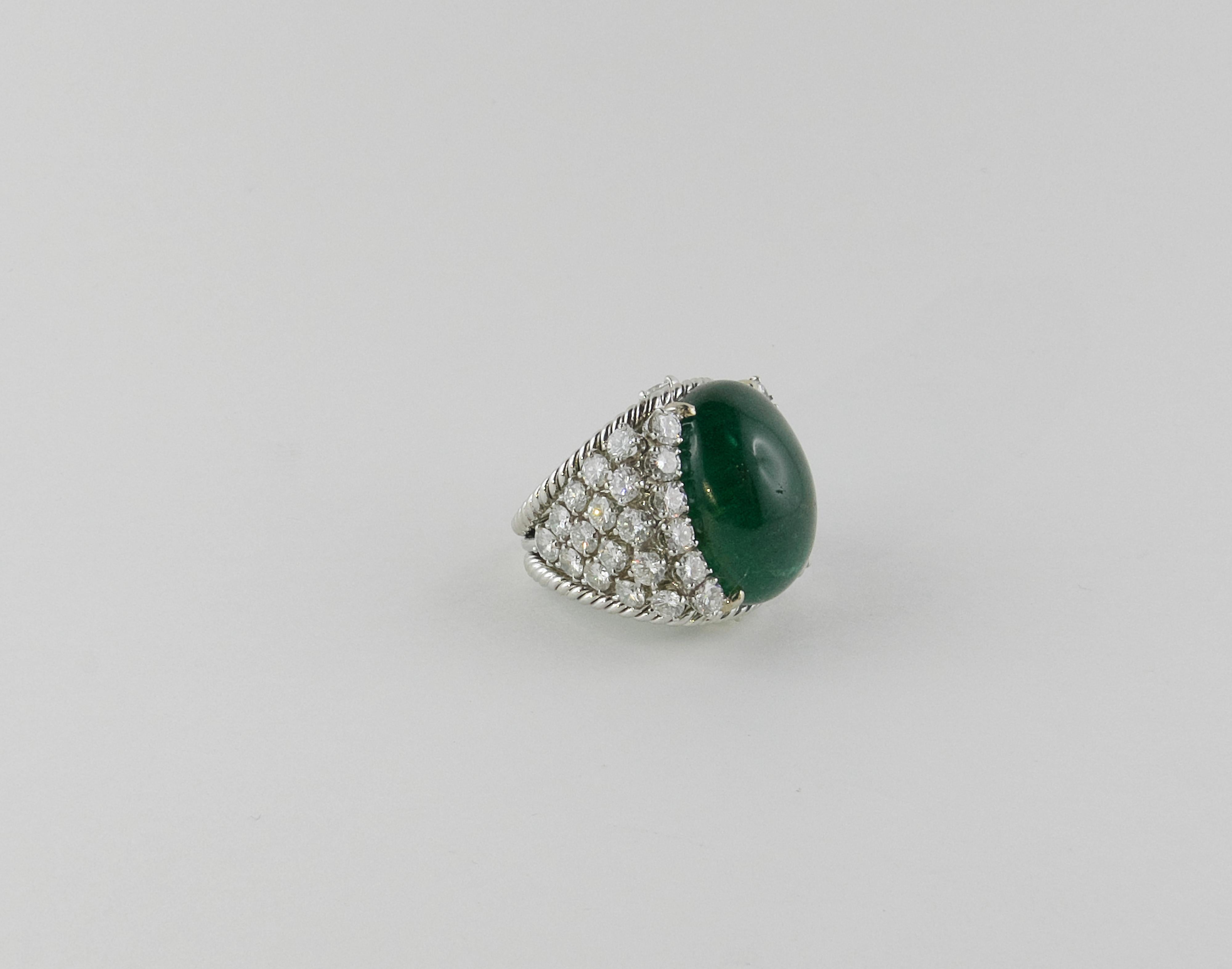 A deep green 27.15 cts Emerald oval cabochon set within a brilliant-cut diamond surround,is the focal point of this  bombé cocktail Ring signed David Webb. To accentuate the centre stone, the completely handmade mounting in Platinum is set with 7