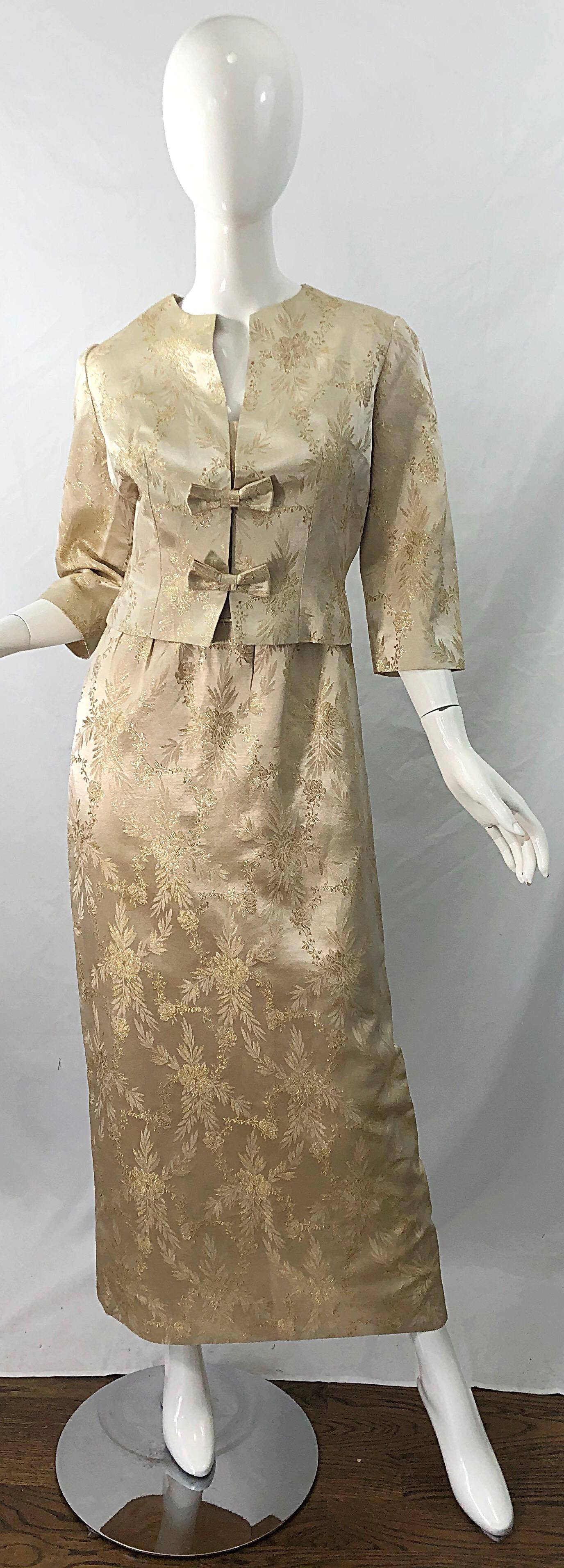 Beautiful demi couture early 1960s gold silk damask two piece evening gown and jacket ensemble ! A beautiful light gold Iridescent silk damask fabric. Cropped jacket features two bows with hook-snd-eye closures. Sleeveless dress with a fitted