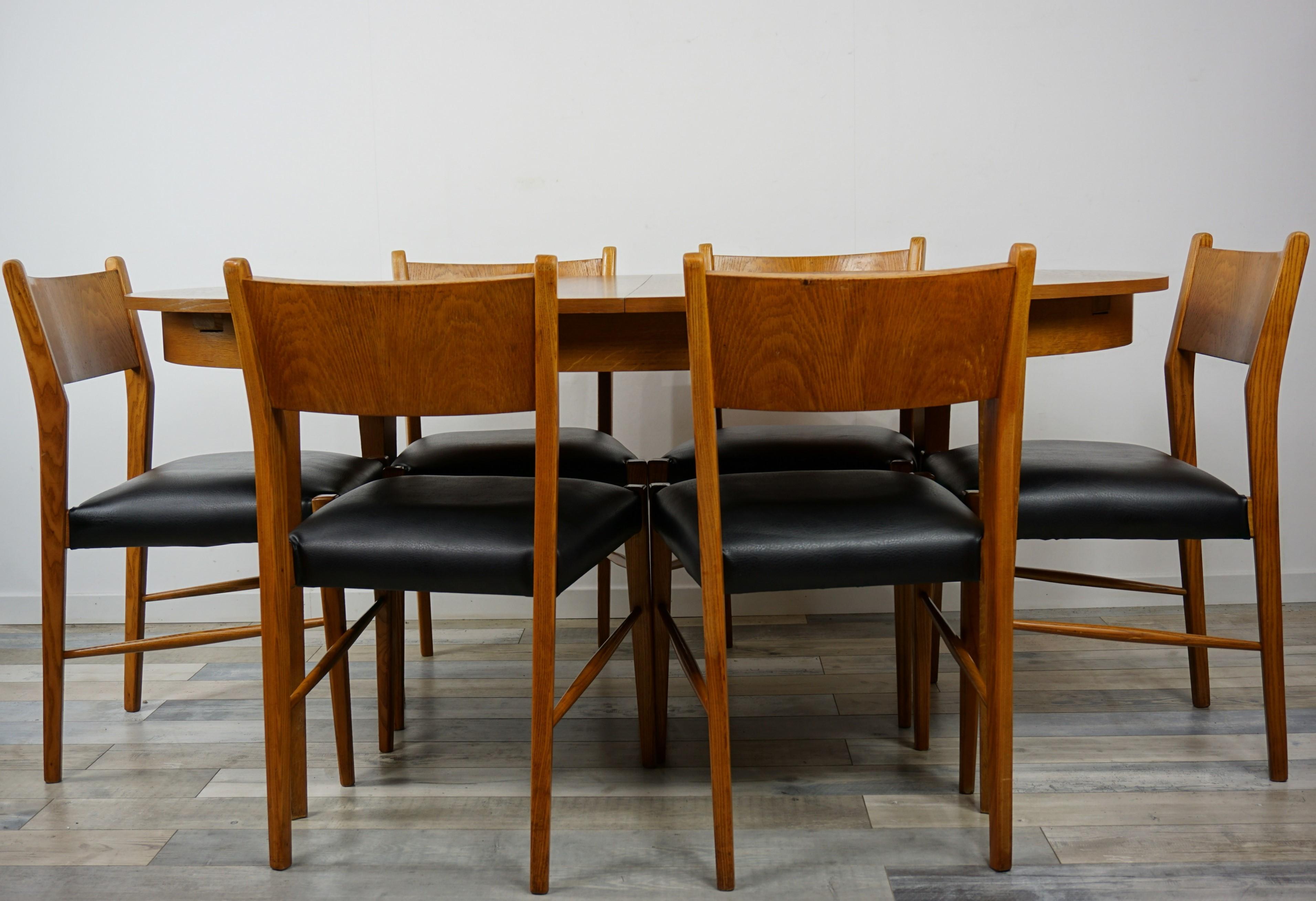 1960s dining set composed of a wooden table, finely worked compass feet, an oval tray of 160cm / 100cm with integrated extension thus adding a length of 80cm, without scratches or lacks and damages, with its 6 matching chairs: wooden structure and