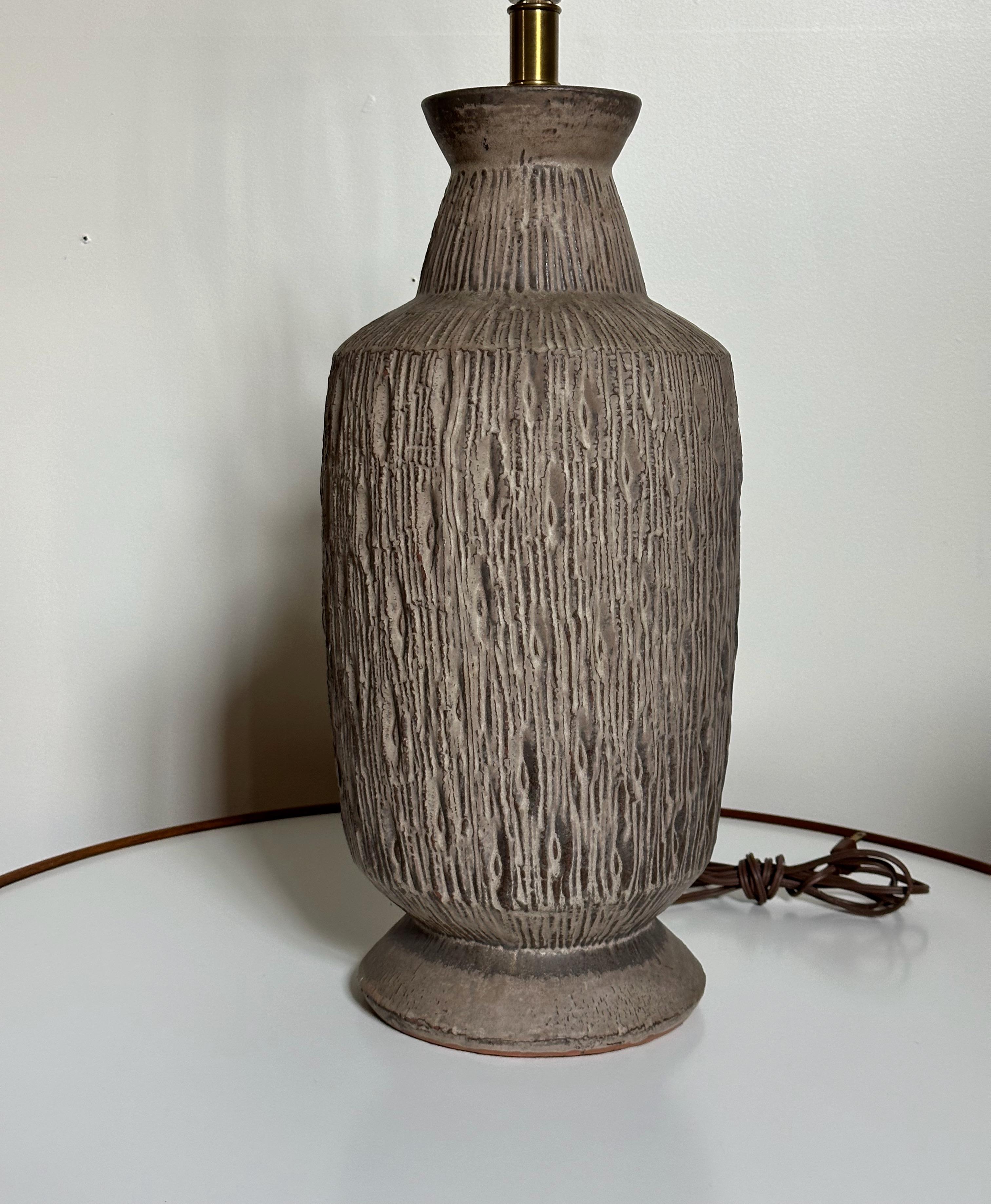Cette lampe de table en céramique Technics des années 1960 présente un design profondément incisé, composé de gris, de noirs et de bruns, qui apporte une touche de charme du milieu du siècle à n'importe quel espace. Fabriqué de manière experte et