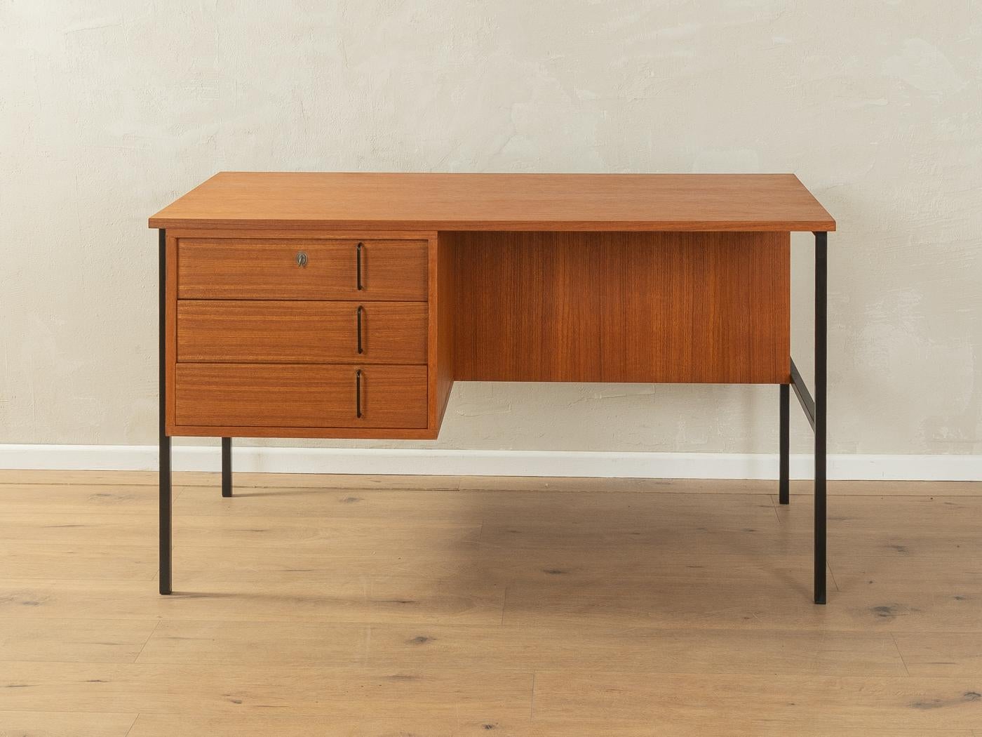 Scrivania indipendente minimalista degli anni '60 di Günter Renkel per Rego Möbel. Corpus in impiallacciatura di teak con tre cassetti, una libreria sul retro e piedi quadrati in acciaio nero.

Caratteristiche di qualità:

    ottima lavorazione
   