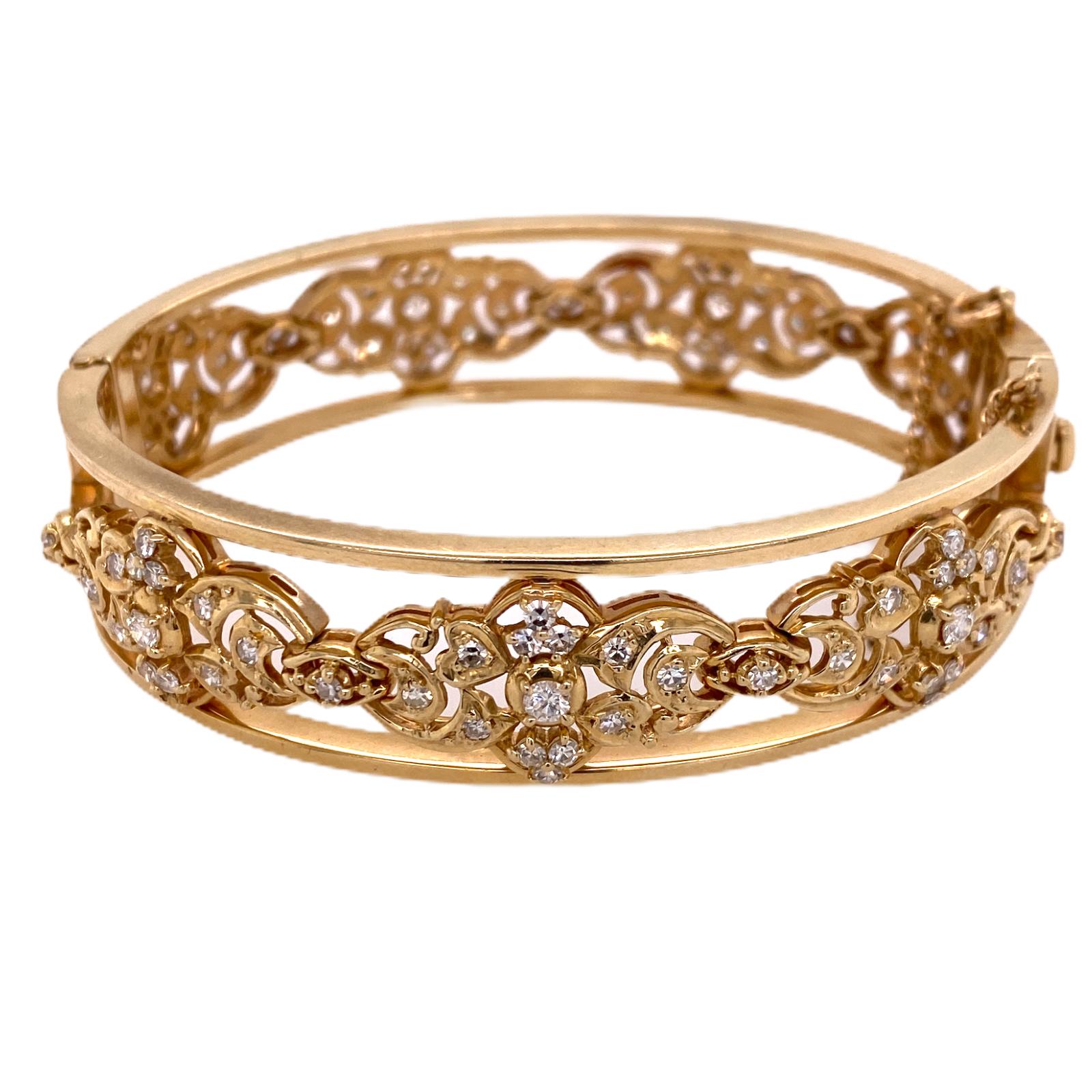 1960's diamond bangle bracelet fashioned in 14 karat yellow gold. The bangle features 97 round brilliant cut diamonds weighing 2.00 carat total weight and graded G-H color and SI clarity. The open design bangle measures .60 inches in width, and 7