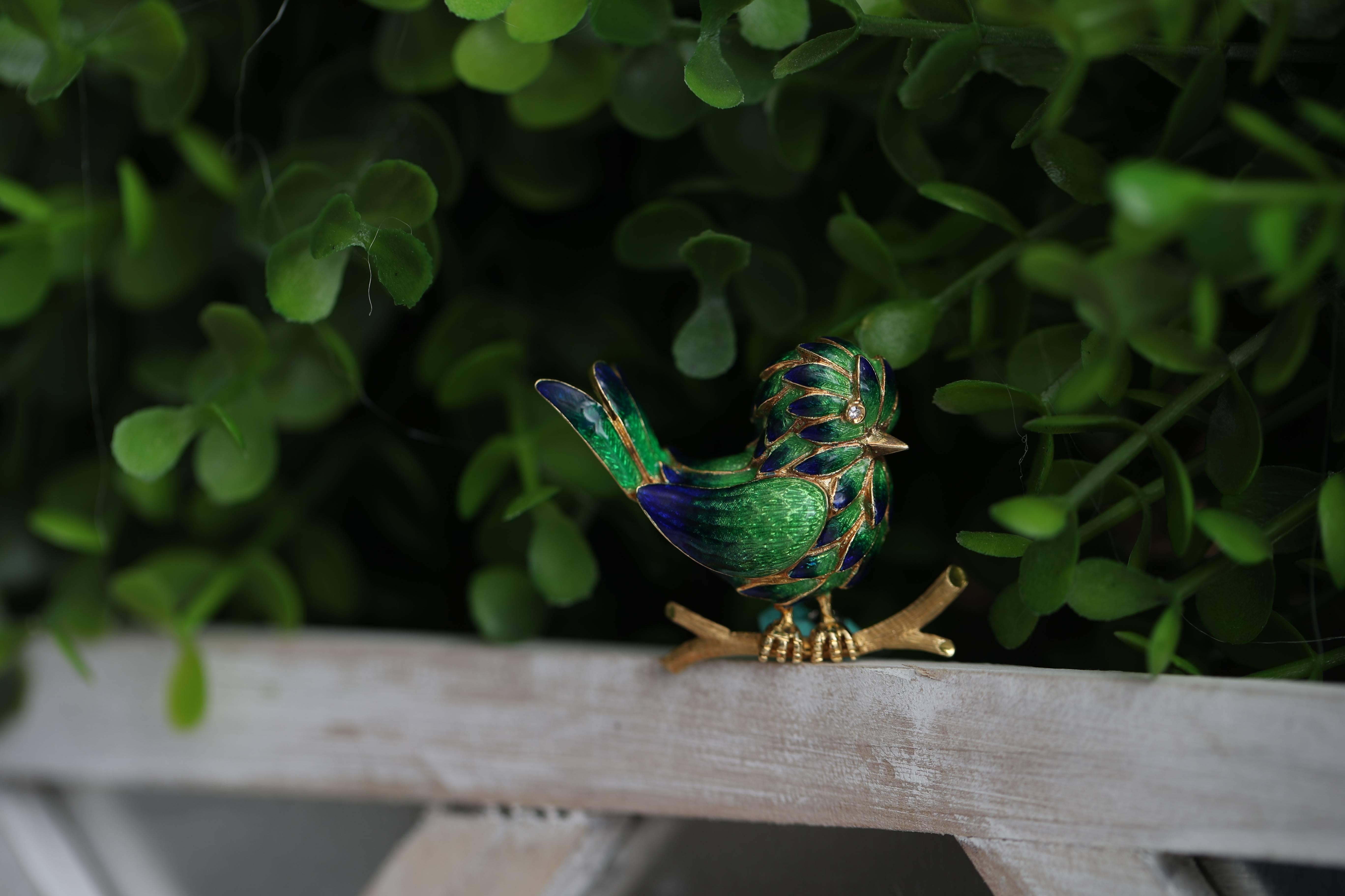 1960s Enamel, Diamond and 18 Karat Yellow Gold Bird Brooch, Lapel Pin

Features an Exquisitely coloured Enamel Bird sitting on an 18 Karat Gold Branch. This Colorful Bird has rich, Emerald Green Plumage. The Tips of the Tail feathers, Wings and Body