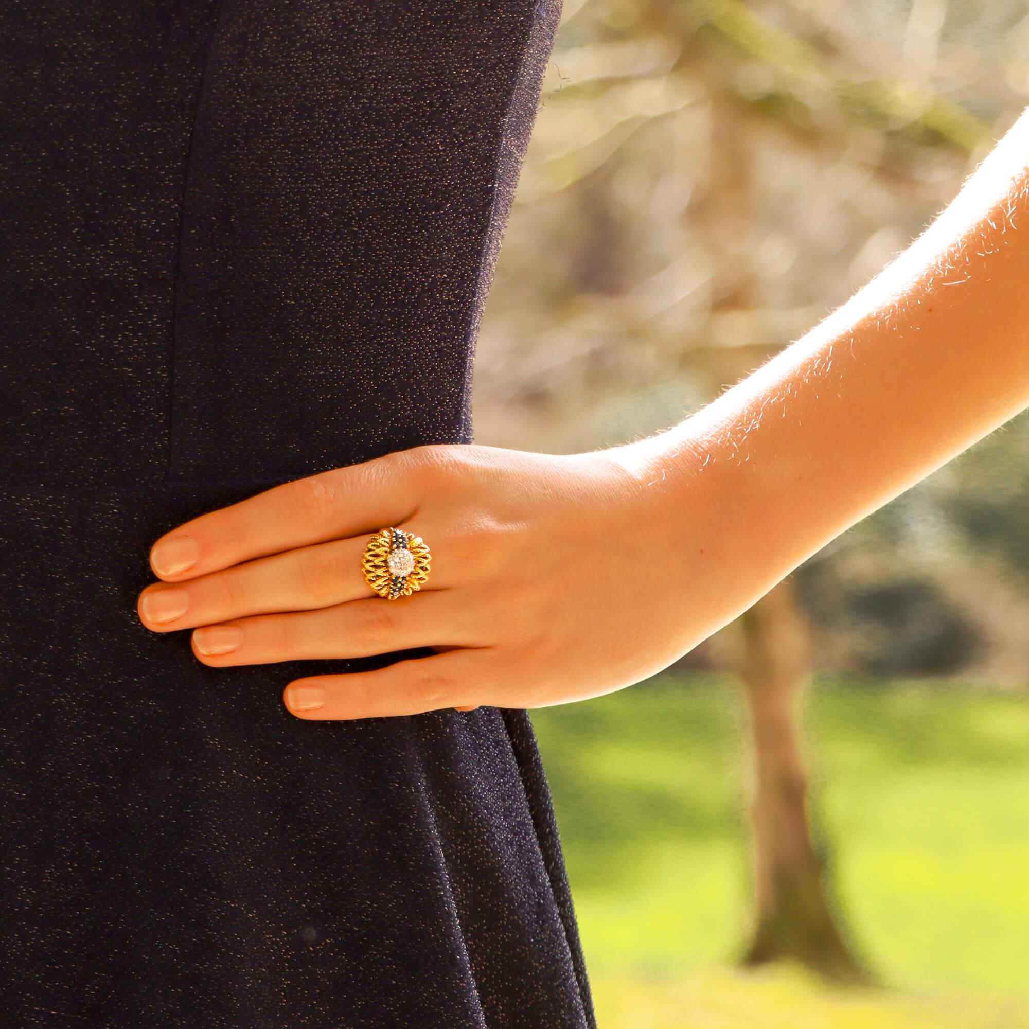 A rather unique early 1960's diamond and sapphire floral cocktail bombe ring set in 18k yellow gold.

This beautiful piece is centrally set with a cluster of 20 round brilliant cut diamonds which gives the illusion of one larger diamond. To each