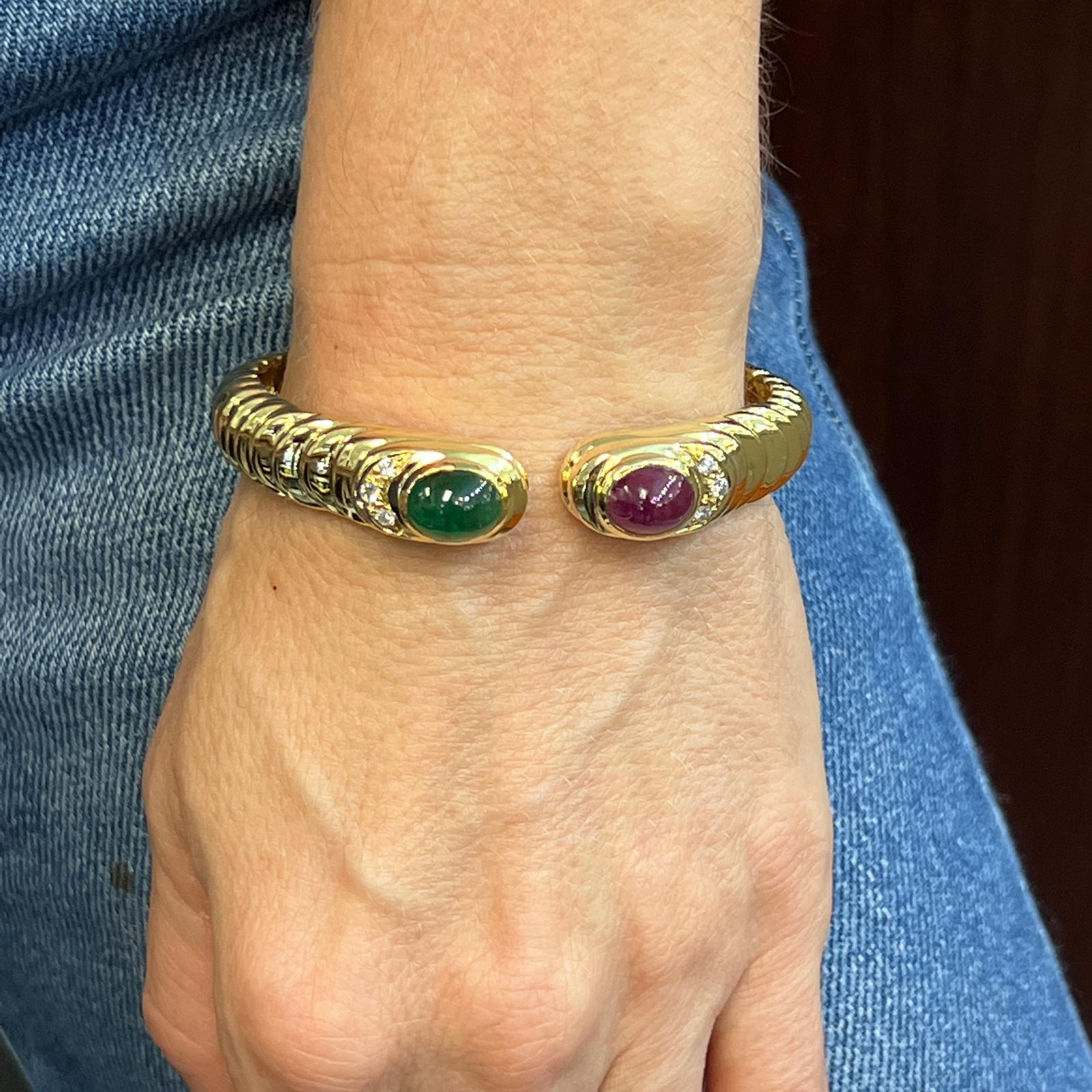 Beautiful cabochon ruby and emerald gemstone cuff bracelet fashioned in 18 karat yellow gold. The 1960's vintage cuff features natural cabochon ruby and emerald gemstones weighing approximately 6.0 carat total weight and 6 round brilliant cut
