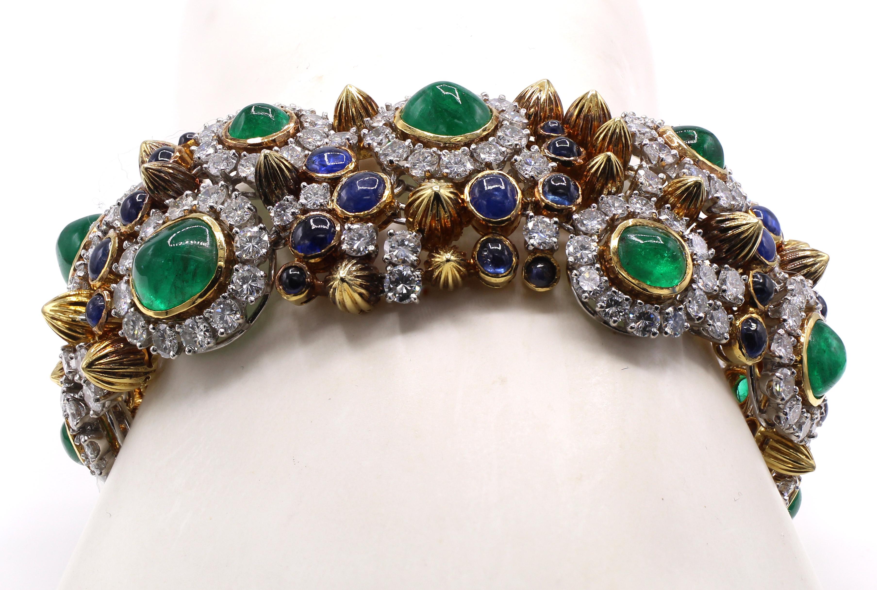 This amazing, unique and bold 1960s bracelet displays a colorful display of bright white and sparkly round brilliant cut diamonds, deep forest green cabochon emeralds and royal blue cabochon sapphires. Beautifully designed and masterfully