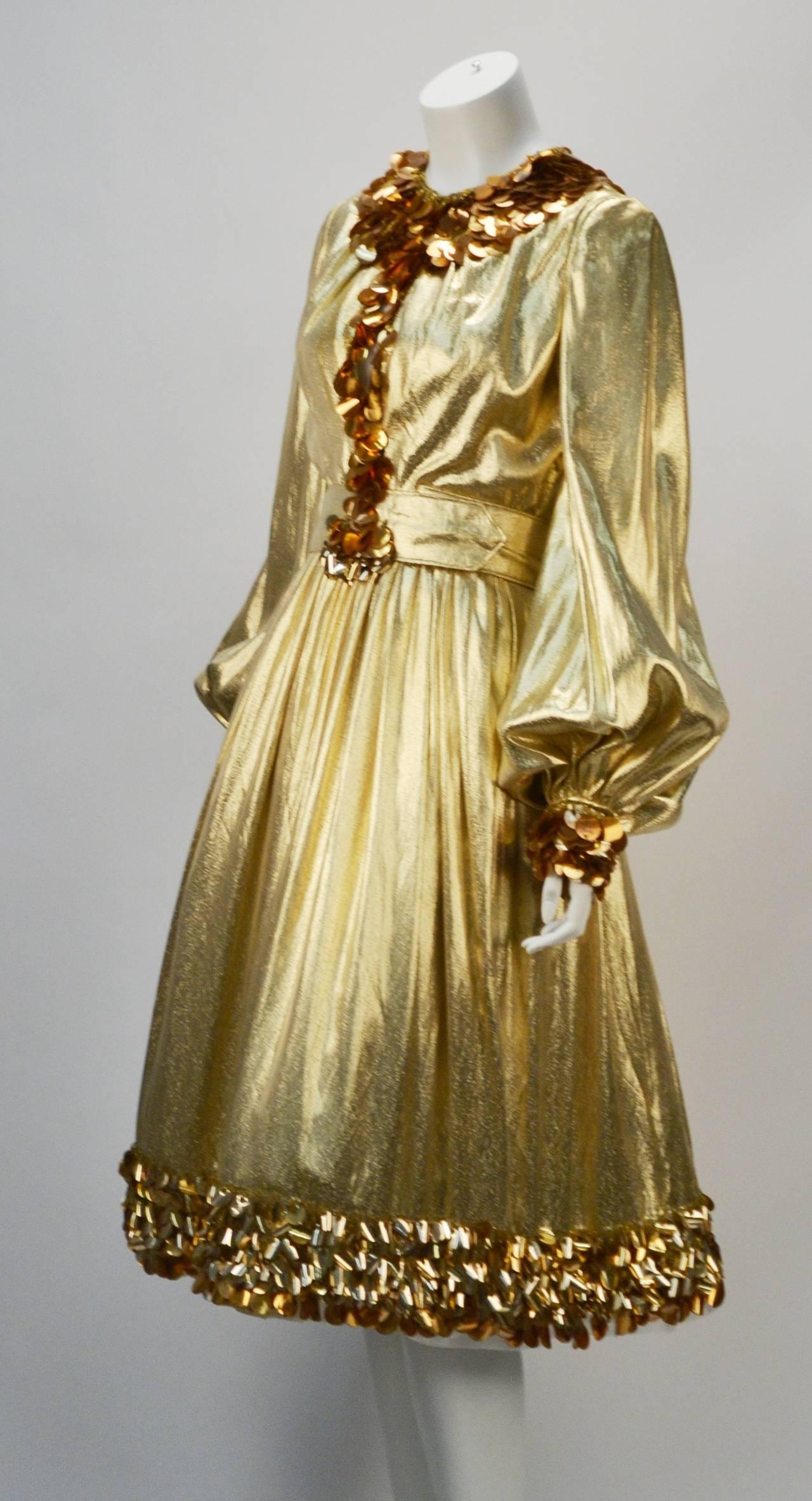 Make a statement in this 1960's fantastic Donald Brooks long sleeve gold metallic evening dress! Gold sequin and beaded trim down the neckline, the center front, around the skirt hem, and around the sleeve cuffs.The dress has a coordinating belt