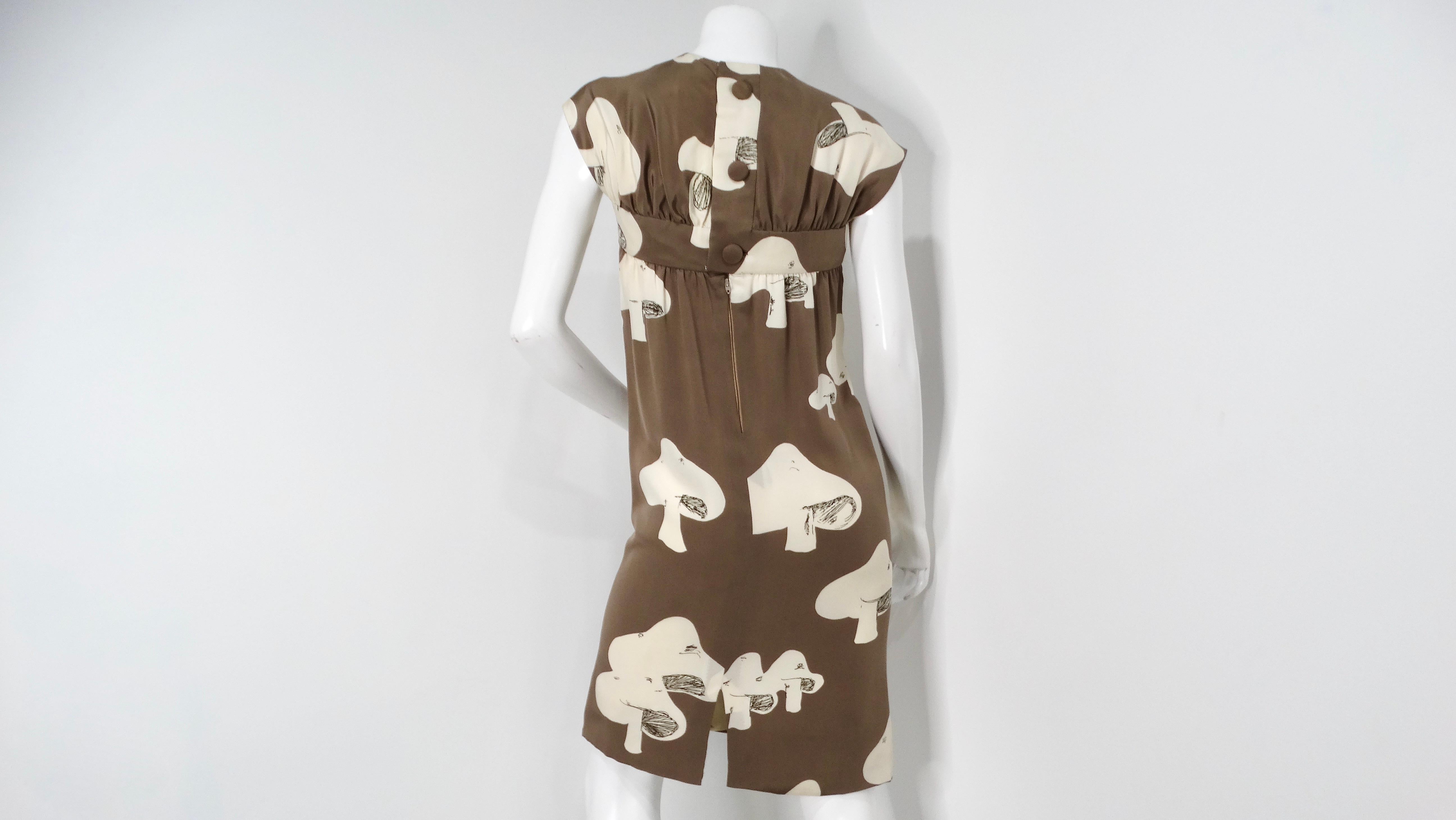 Step into a whimsical world of 1960s fashion with this exquisite Donald Brooks Mushroom Print Taupe Dress. This enchanting garment showcases a soft taupe canvas adorned with playful white mushroom motifs, seamlessly blending the charm of nature with