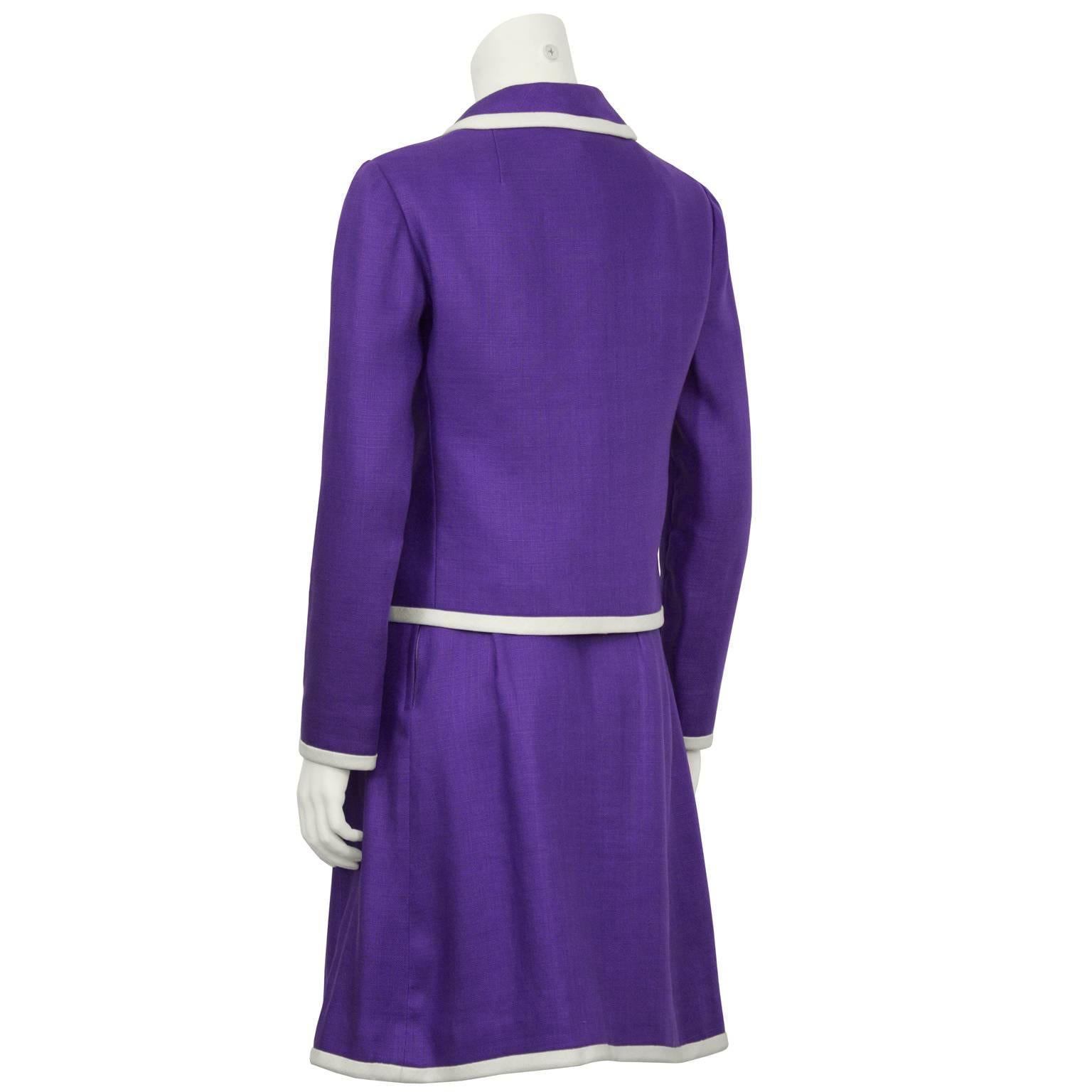 Adorable Donald Brooks purple linen 3-piece skirt suit from the 1960's. The suit is detailed throughout with white piping along the hem, collars, and pockets. The crop-style jacket buttons down the front with cream buttons. The matching shell has a