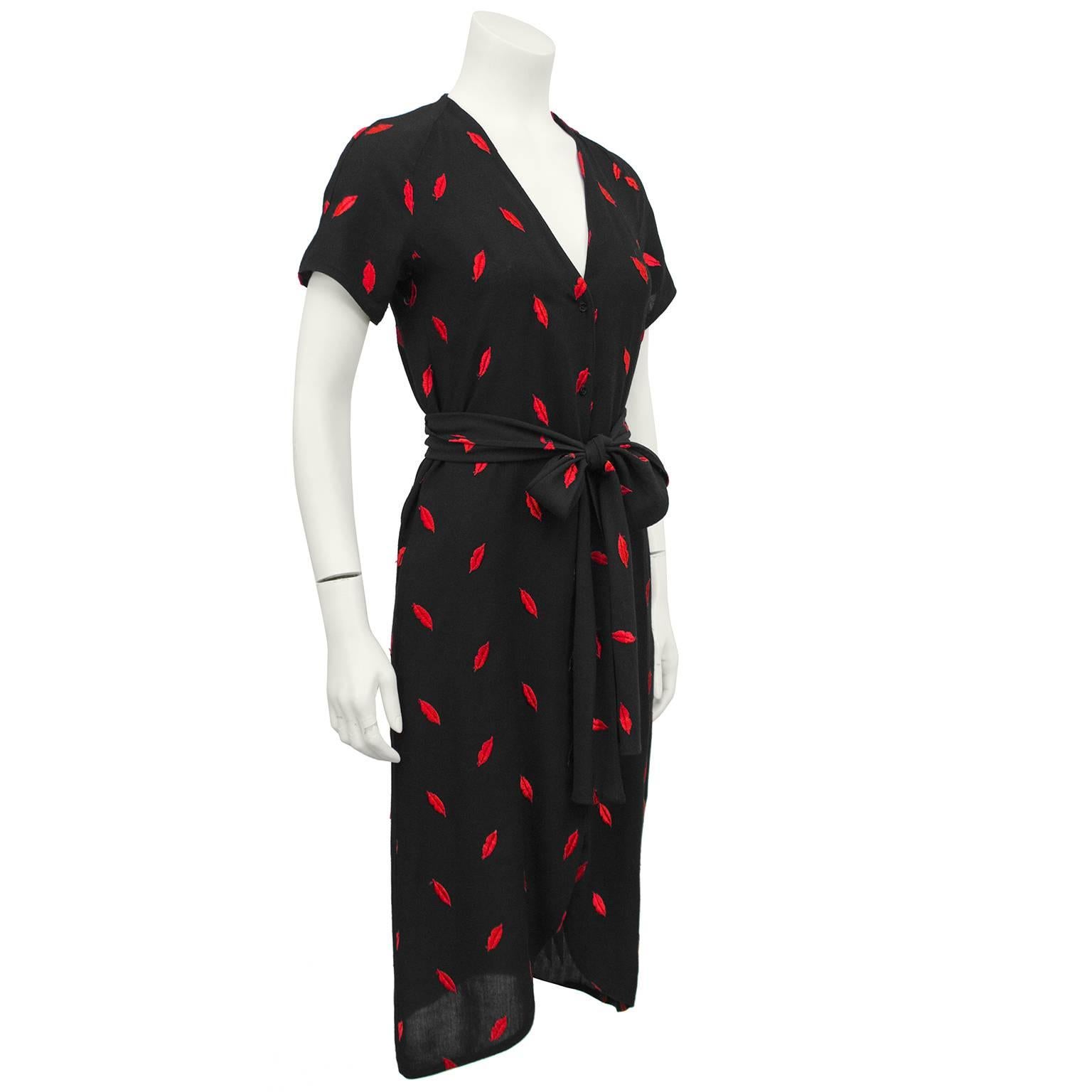 This cotton red lip printed dress by Paris fashion house Dorothee Bis is the ultimate wardrobe must have. The short sleeved, midi length dress has black buttons up the front and is accented with a wide sash belt made from the same red lip stitched