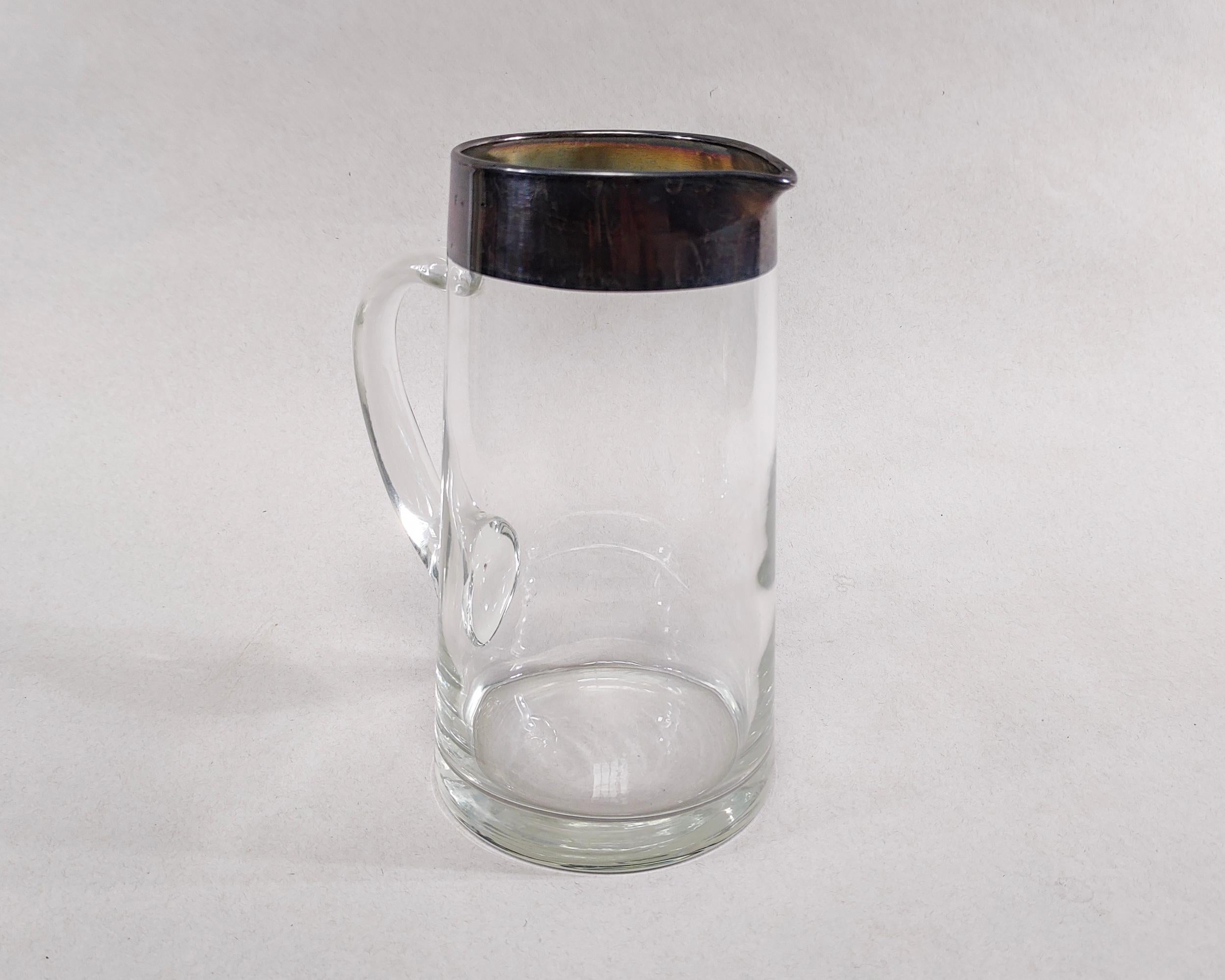 Vintage Dorothy Thorpe 52 oz. hand blown glass pitcher circa 1960s. Subtle taper with iconic thick sterling silver band around the rim.  Overall great condition, natural darkened patina on silver, couple of chips to silver as shown in photo.

8-5/8