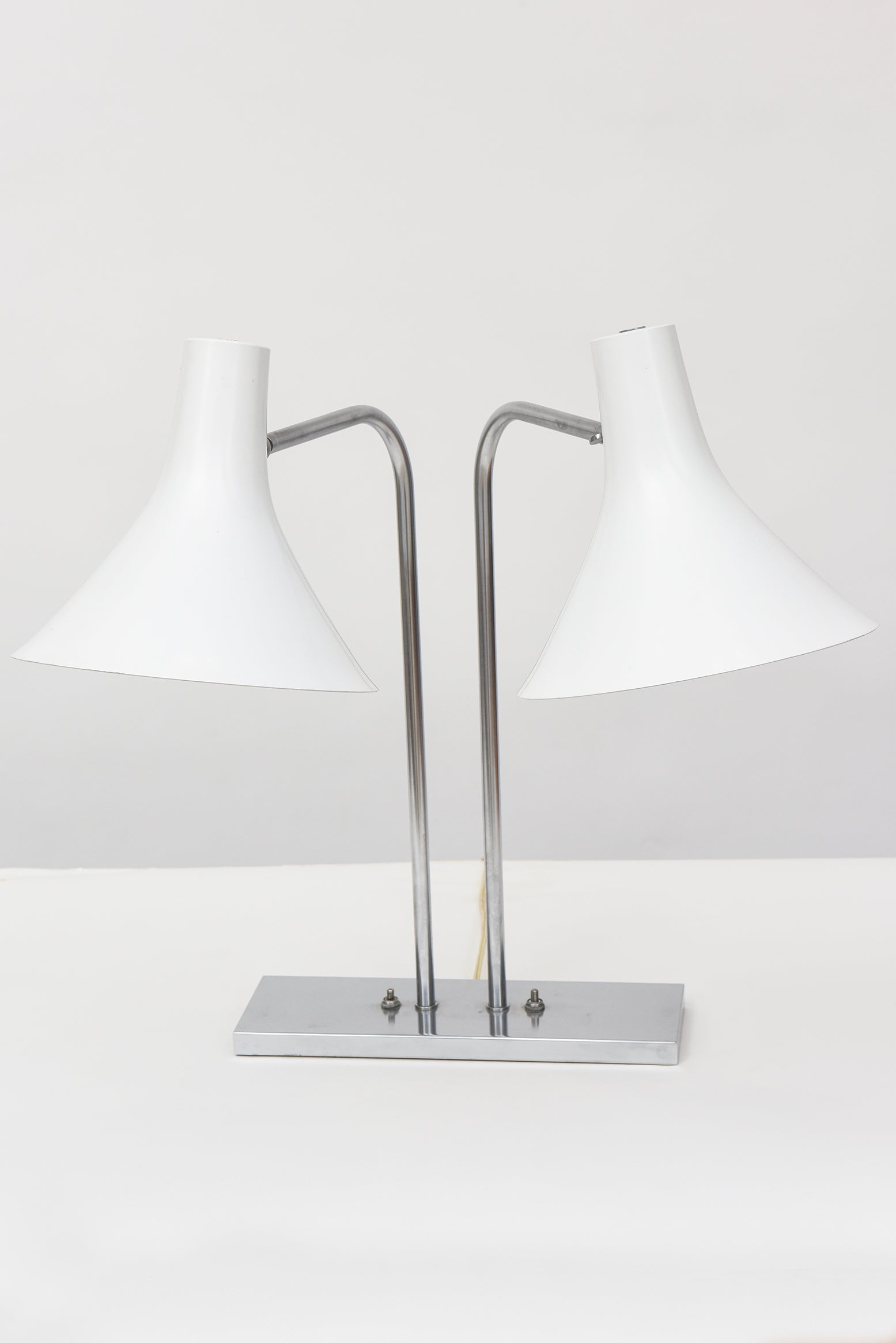 A timeless 1960s-designed double cone desk lamp by Greta Grossman for Nessen Studios with brushed nickel frame and enameled aluminum shades. Shades pivot, swivel, and lock in place to provide a myriad of lighting positions. Two small scratches on