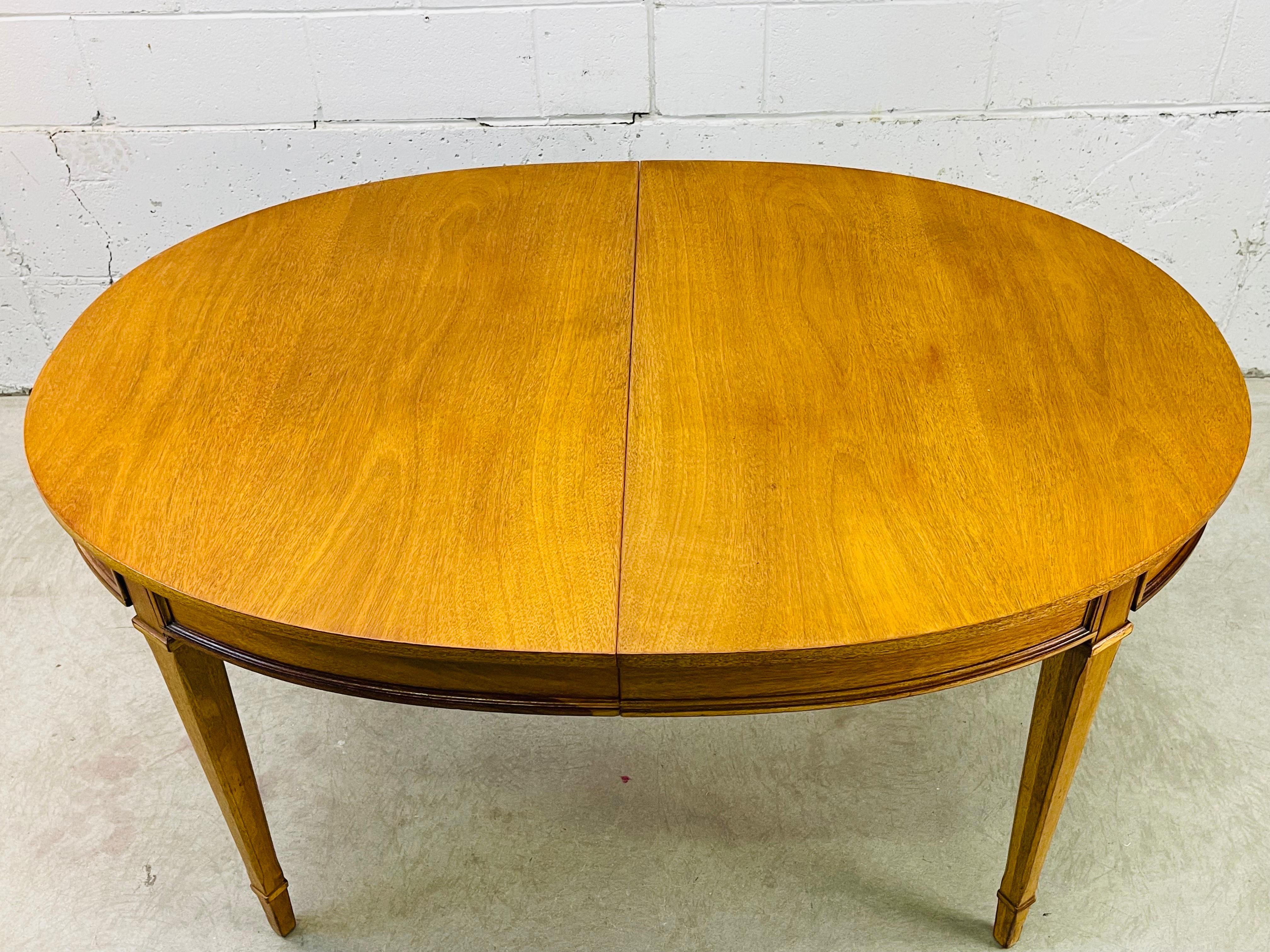 Vintage 1960s Drexel Furniture oval mahogany wood dining room table from the Triune collection. This table comes with two additional boards, each 12”W. The table fully open with both boards is 80”W. The table has beautiful mahogany wood grain. Knee