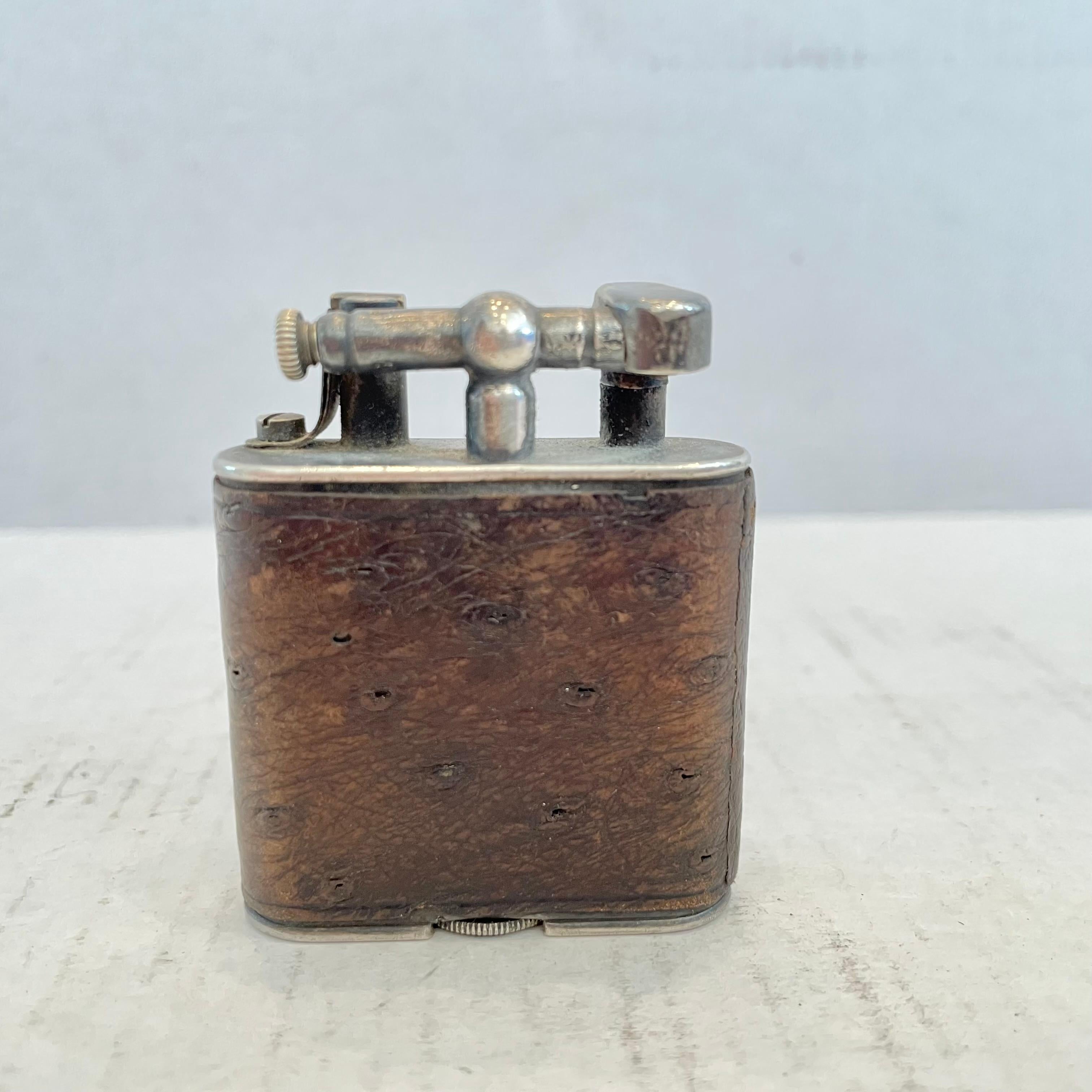 Elegant Dunhill lift arm lighter made in the 1960s. Body wrapped in ostrich leather that has a perfect patina. Amazing texture and practical size perfect for a desktop or for your pocket. 