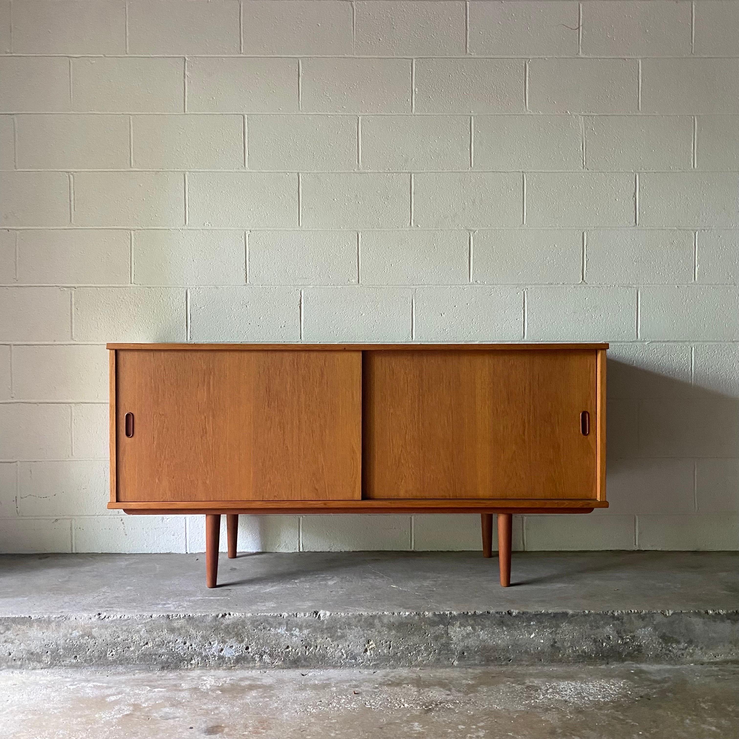 This is an incredible Danish teak sideboard by Dyrlund, ca. 1960’s - made in Denmark. It features two sliding doors with shelves on both sides and a felt-lined drawer for serving ware. 

.