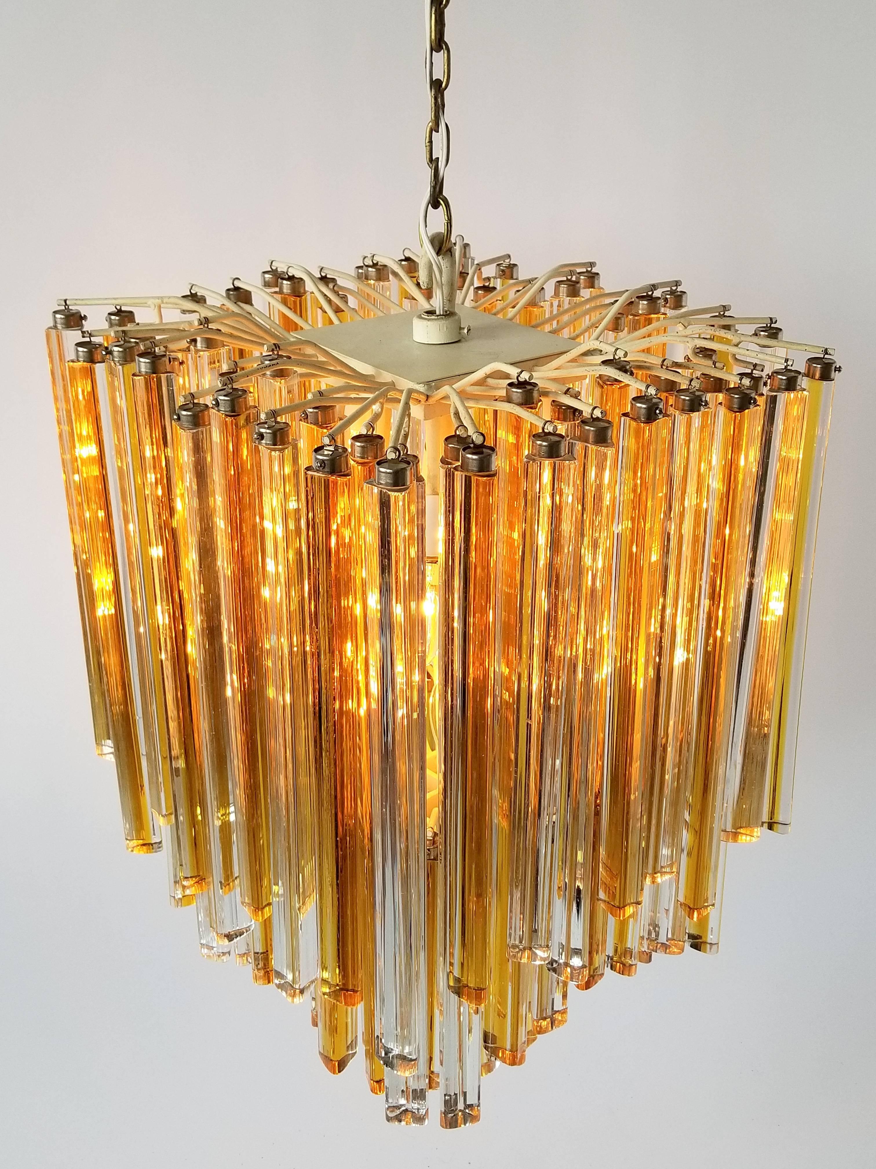 Thick optical quality glass prisms 'Triedri' in clear and amber tone of different length hooked on a handmade steel frame enameled in an ivory finish. 

Particular well designed sturdy hardware on glass for hanging it to structure. 

Contain 16