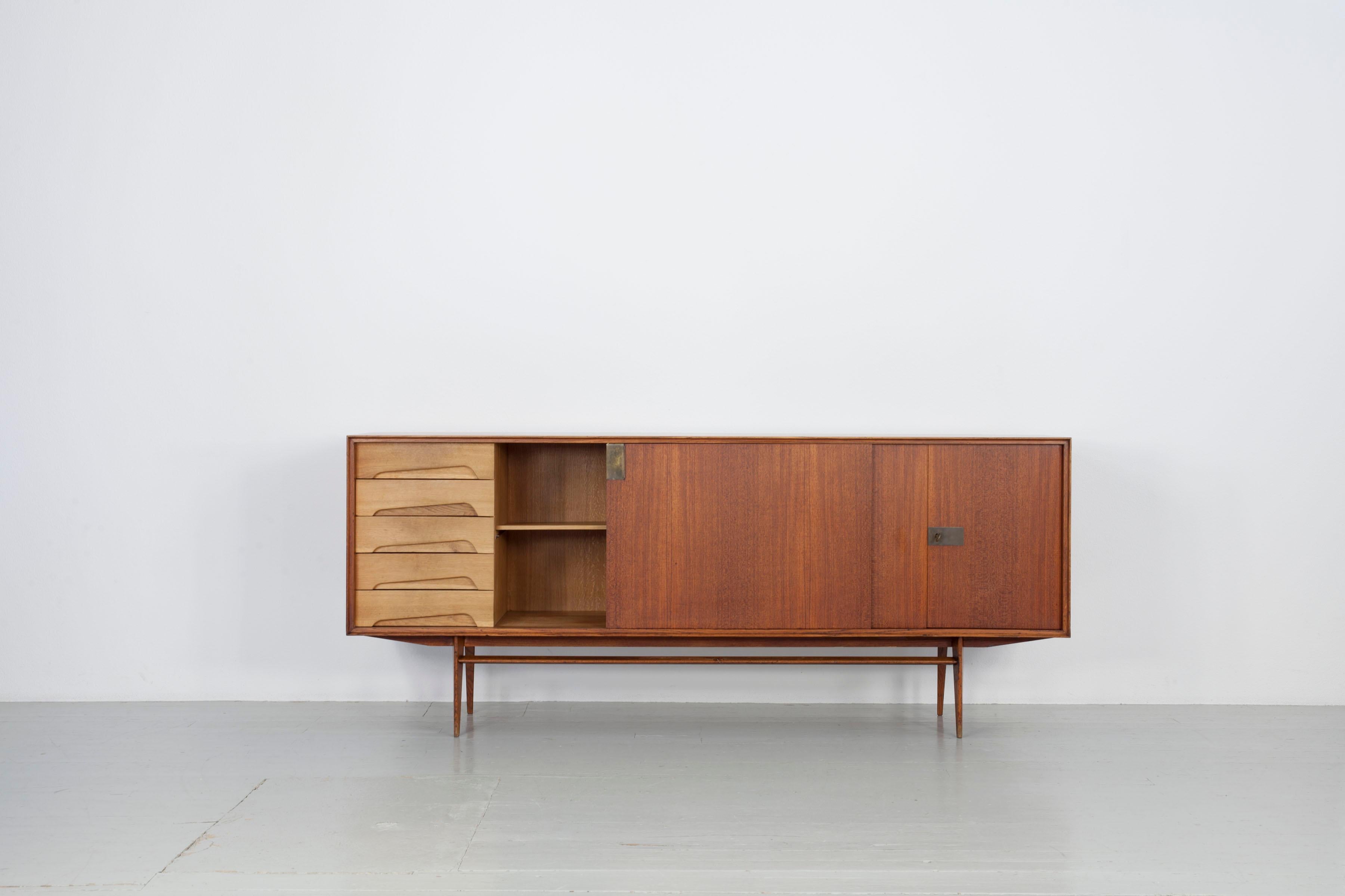 This sideboard was made with teak and brass details. The versatile sideboard offers plenty of storage space and is in very good vintage condition. Edmondo Palutari worked in-house at Dassi Mobili Moderni (DMM) in the 1950s, designing a successful