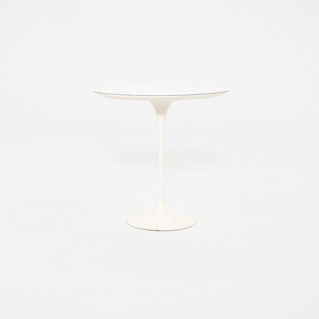 This is a Saarinen Round Side Table, originally designed by Eero Saarinen in 1956. This particular example was produced by Knoll in the USA in the 1960s. The table features a 20-inch white laminate top set on Saarinen's iconic cast aluminum pedestal