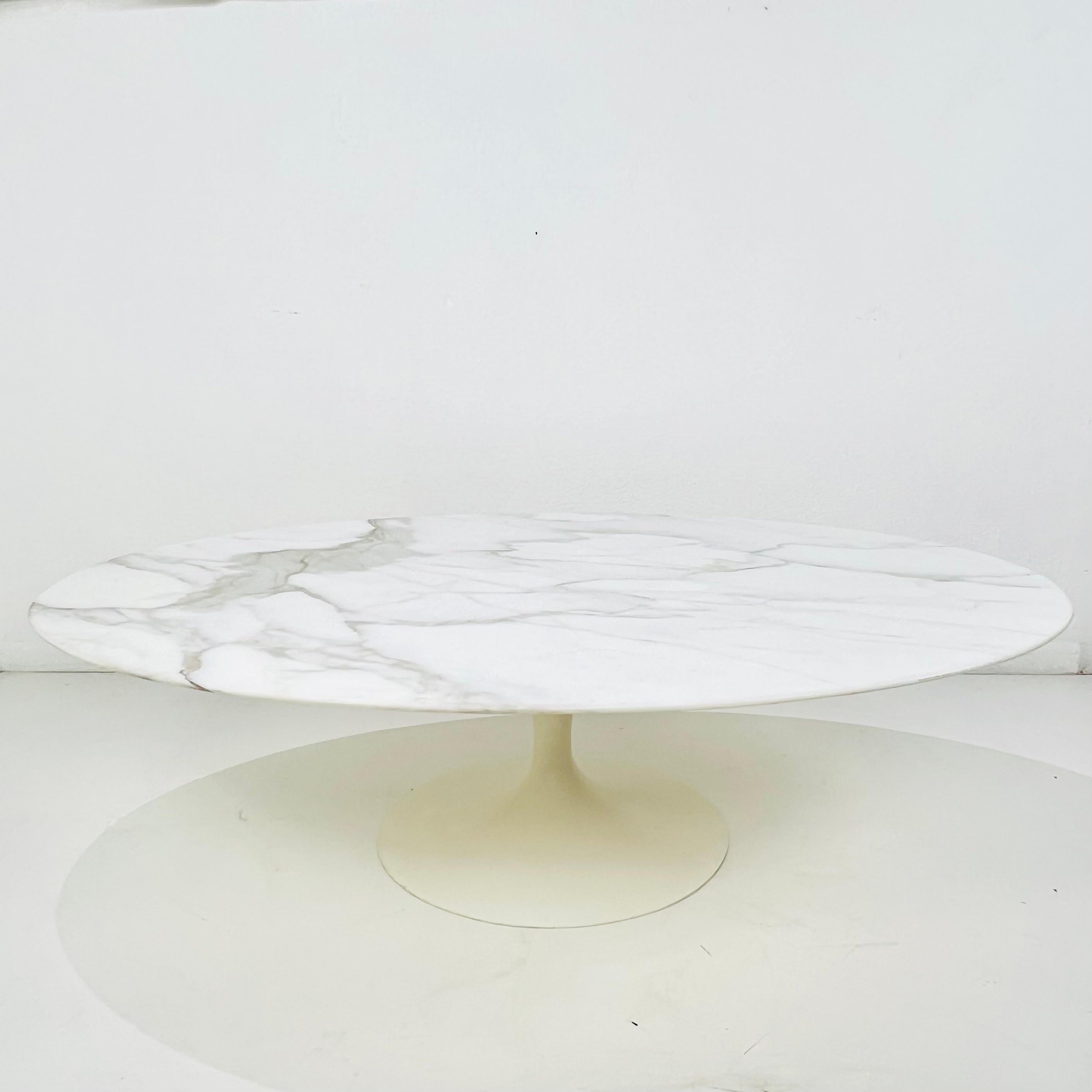 1960s pedestal base coffee table by Knoll. Marble top sits on a white enamel cast iron tulip base. Beautiful veining throughout the marble top. The white enamel cast iron bottom is very heavy and sturdy. Very good condition for its age, with some