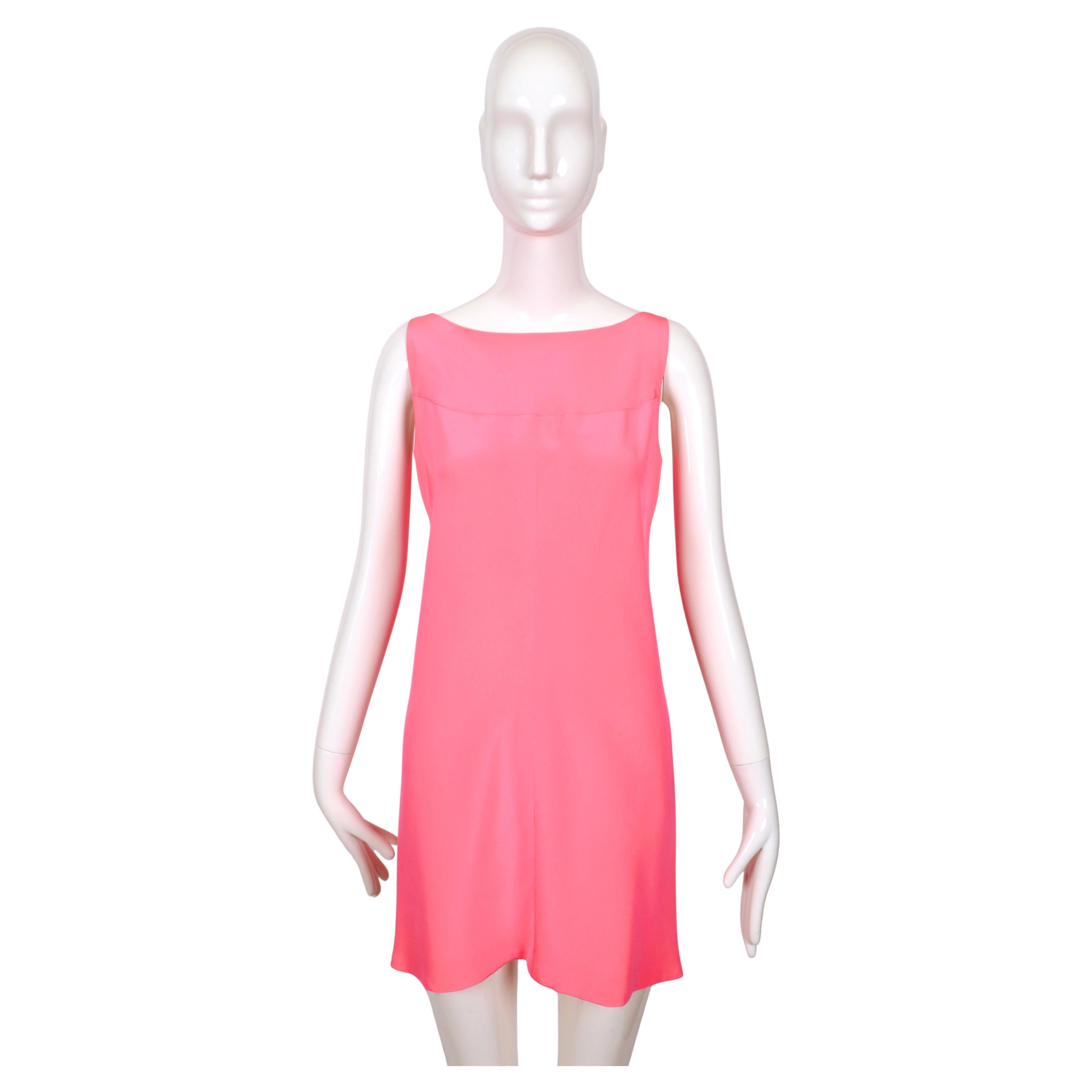 Impresionante vestido de seda diseñado por Cristóbal Balenciaga para el atelier español EISA.  Este vestido es un bello ejemplo del diseño minimalista de mediados de siglo. Confeccionado en un vibrante color rosa, el vestido presenta una sencilla