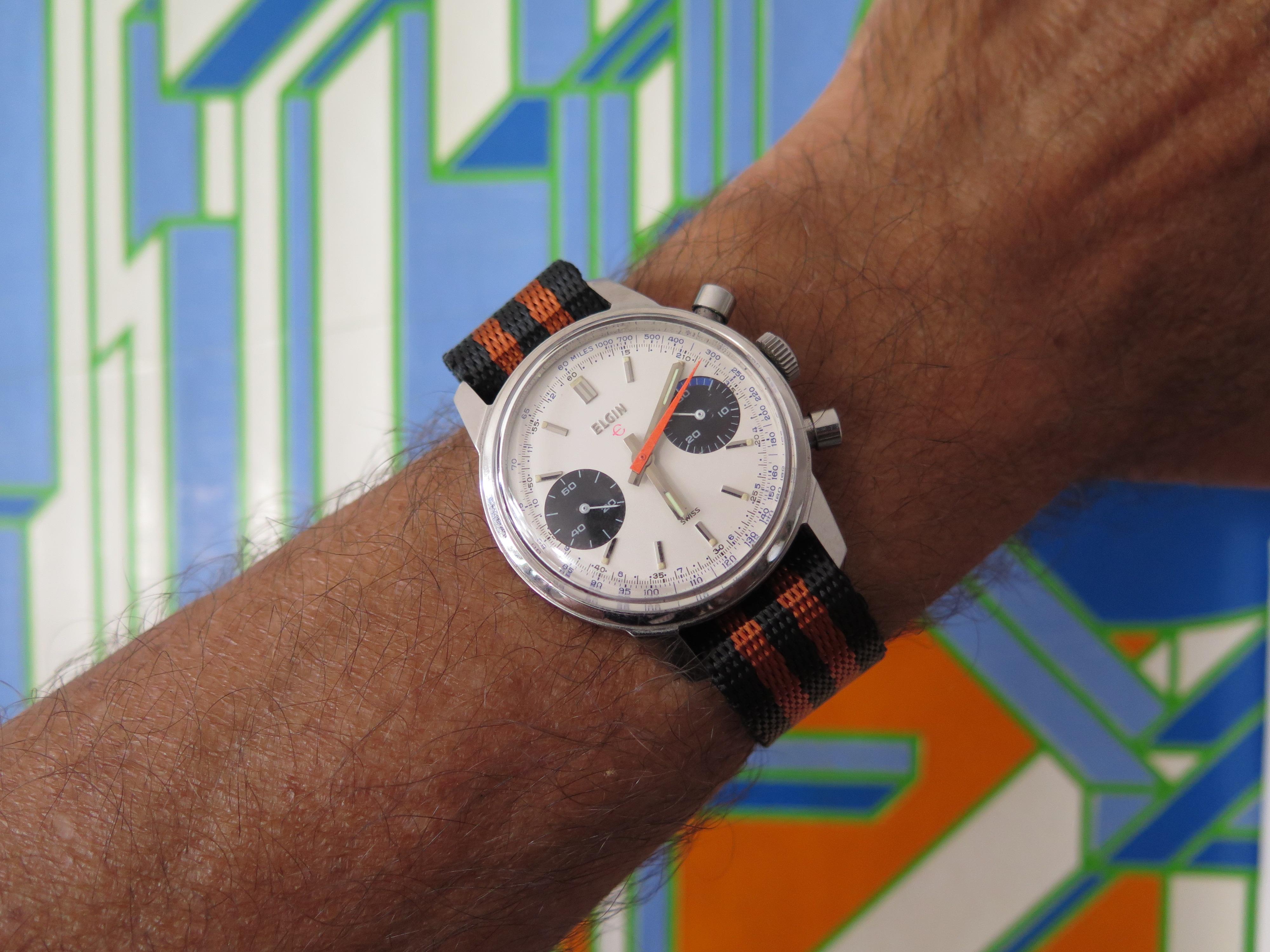 A classic Elgin chronograph ca' 1960's. Featuring a white dial with slightly sunken subsidiary black dials, orange second hand. Measuring 36mm diameter without crown and approx. 43 mm lug to lug. This watch has a solid feel on the wrist. Powered by