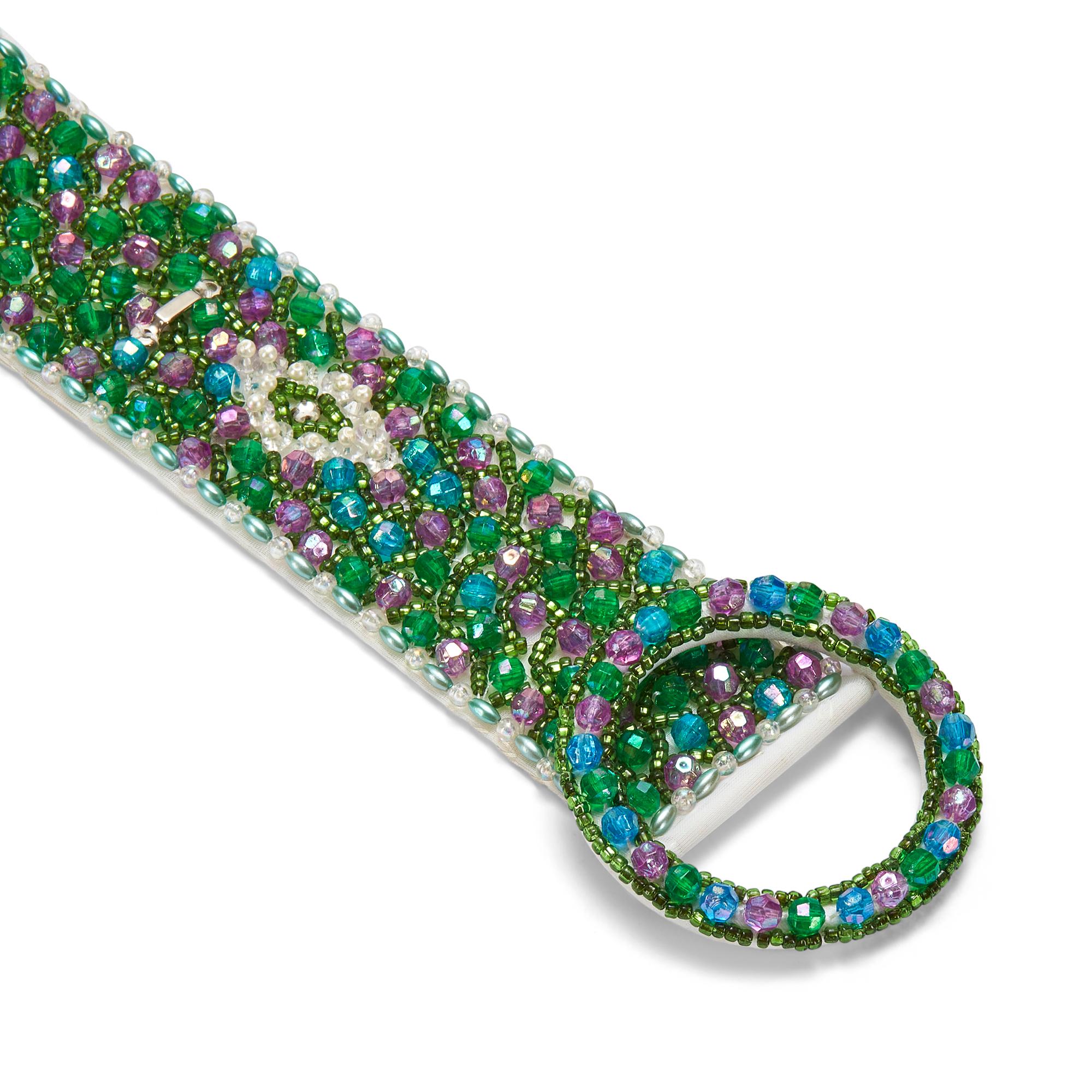 This lavish embellished cloth belt was made in the 1960s and remains in excellent vintage condition, without a bead out of place. It is covered all over with beads of varying sizes in lustrous blue, green and pink-purple. Tiny pearls and sheer,
