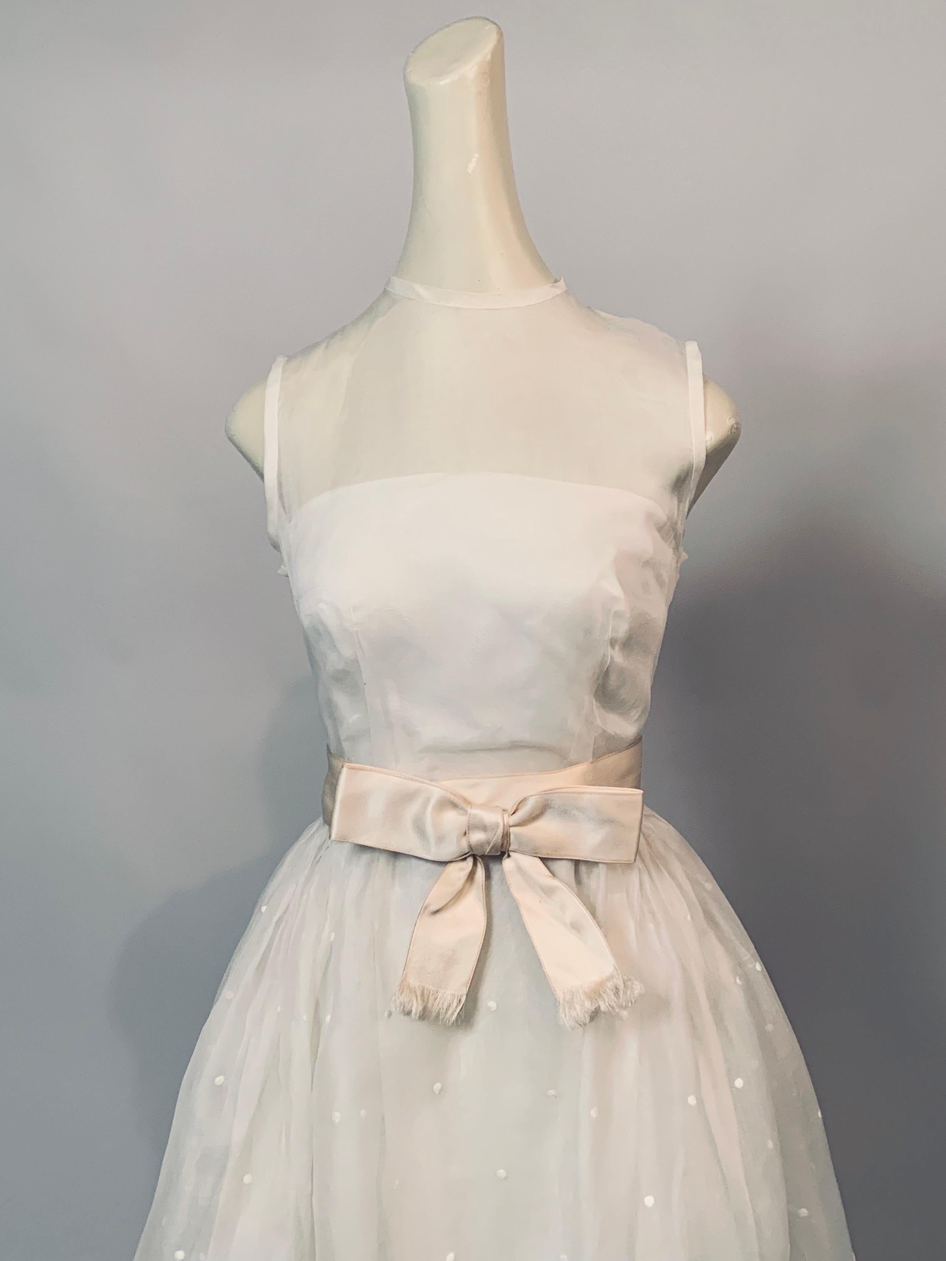 This beautiful embroidered white silk organza evening dress has a strapless taffeta bodice and petticoat with a sheer silk organza layer creating a sheer bodice and a beautiful embroidered full skirt.   It is embroidered with white dots and  a deep