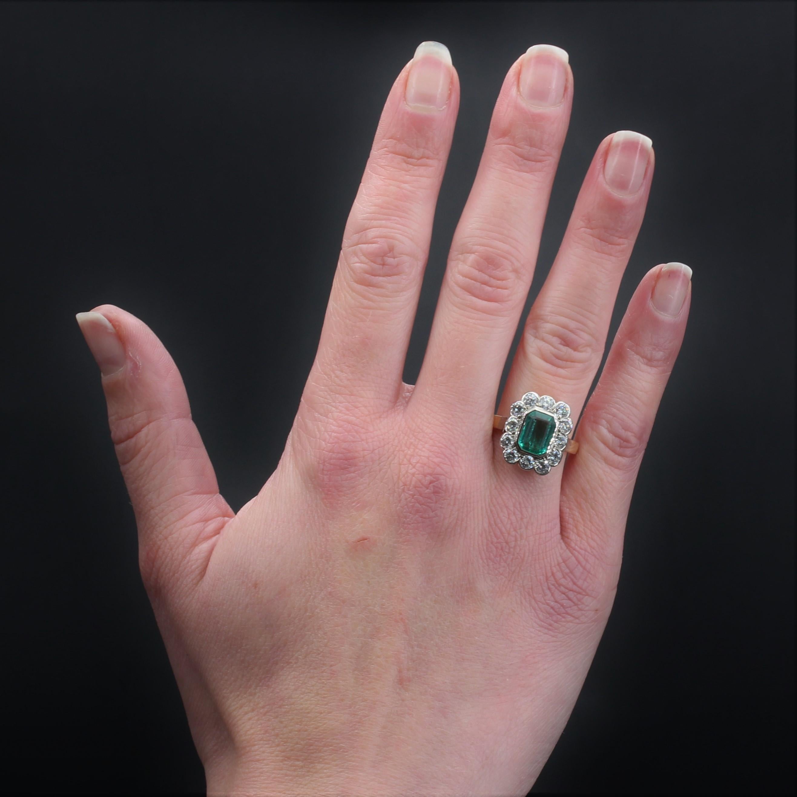Bague en or jaune 18 carats et en platine.
Bague ancienne, élégante et intemporelle, elle présente une monture rectangulaire ornée au centre d'une émeraude taillée en degrés en serti clos, et entourée de diamants modernes taillés en brillant. Le