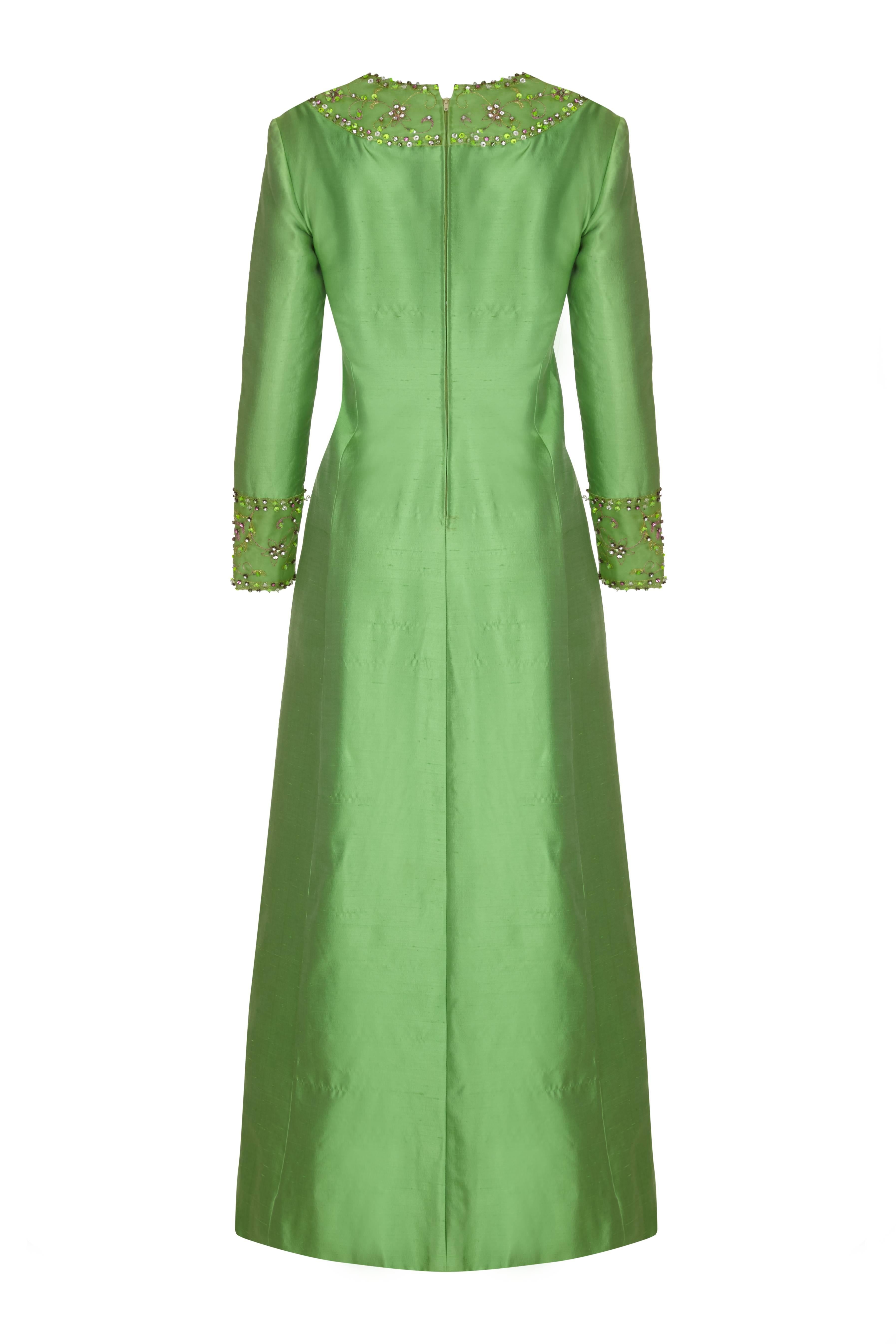 This stunning full length silk vintage dress in emerald green is by American label Gino Charles for Malcolm Starr and is of superb quality. This opulent piece has intricate beading with prong set rhinestone embellishment in green, pink and crystal