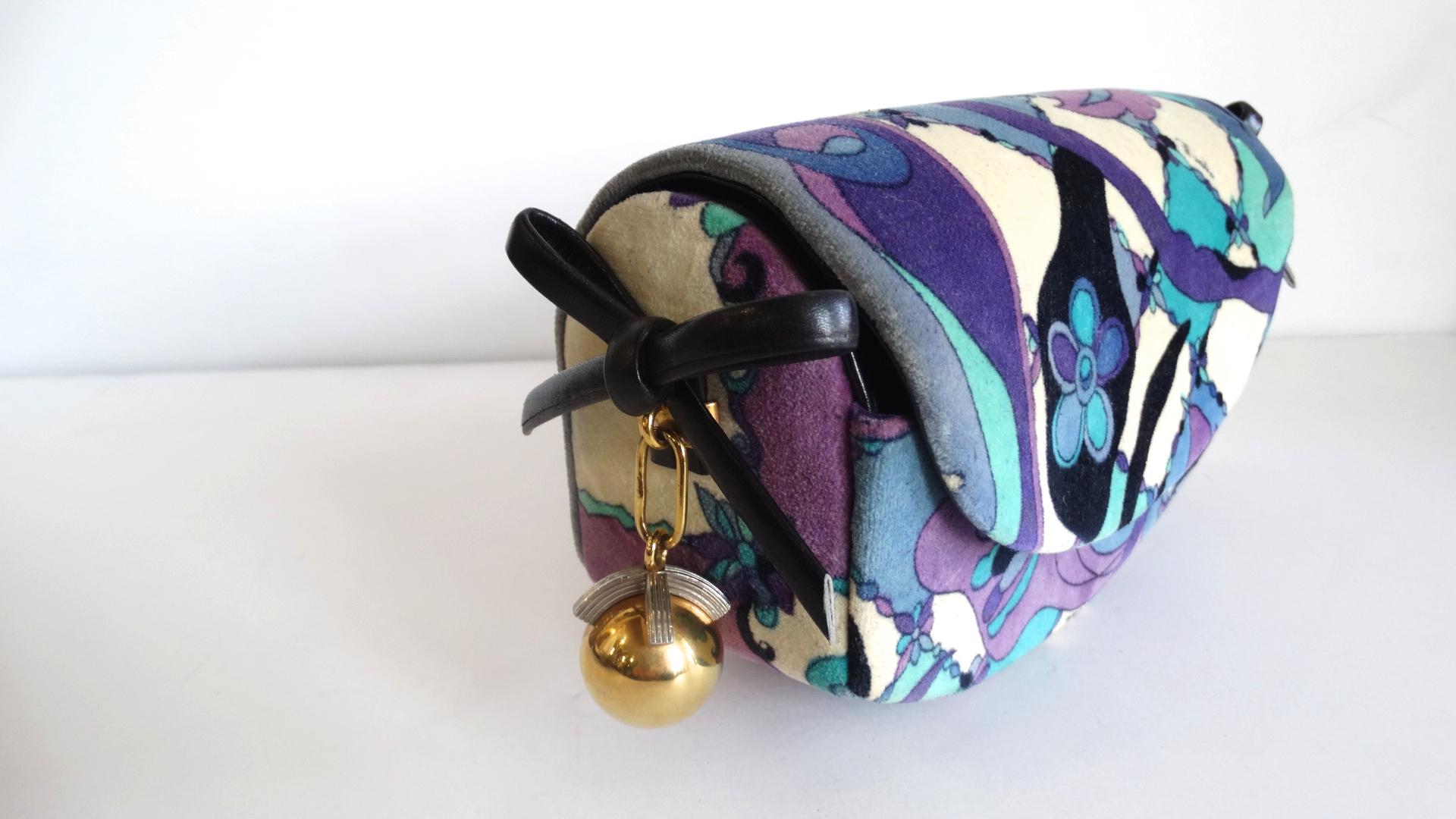 More Pucci Please! Circa 1960s, this Pucci clutch features one of his many signature abstract floral patterns in teal, and shades of purples and blues. The sides include dark navy leather bows and a gold plated ball charm. Front flap opens to reveal