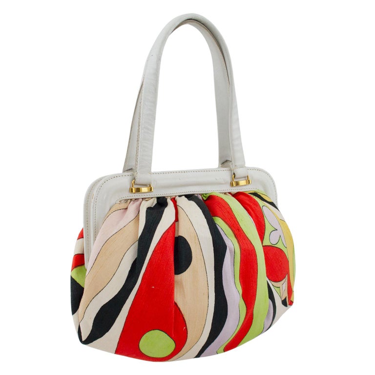Adorable Emilio Pucci frame bag from the 1960s. Features the iconic Pucci multi colour abstract pattern in raw silk with Pucci signature. White leather hard frame with gold tone metal interior and white leather top handles. Opens wide and has a deep
