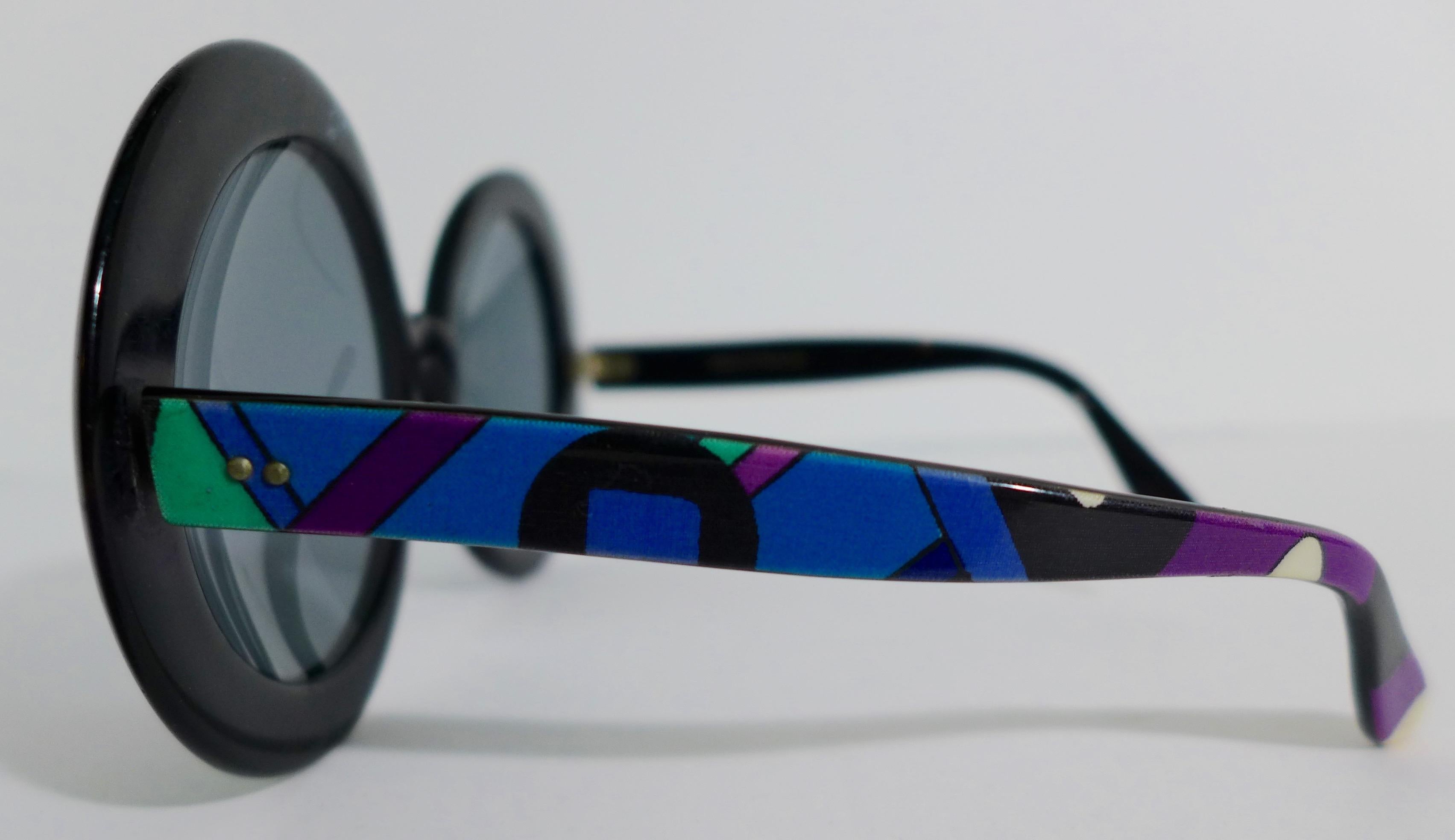 These Emilio Pucci round plastic sunglasses feature a classic blue, green, and purple print. The lenses are black. Made in France. 

Measurements in Inches: 
Width: 6.5 
Height: 3
Length: 5.5