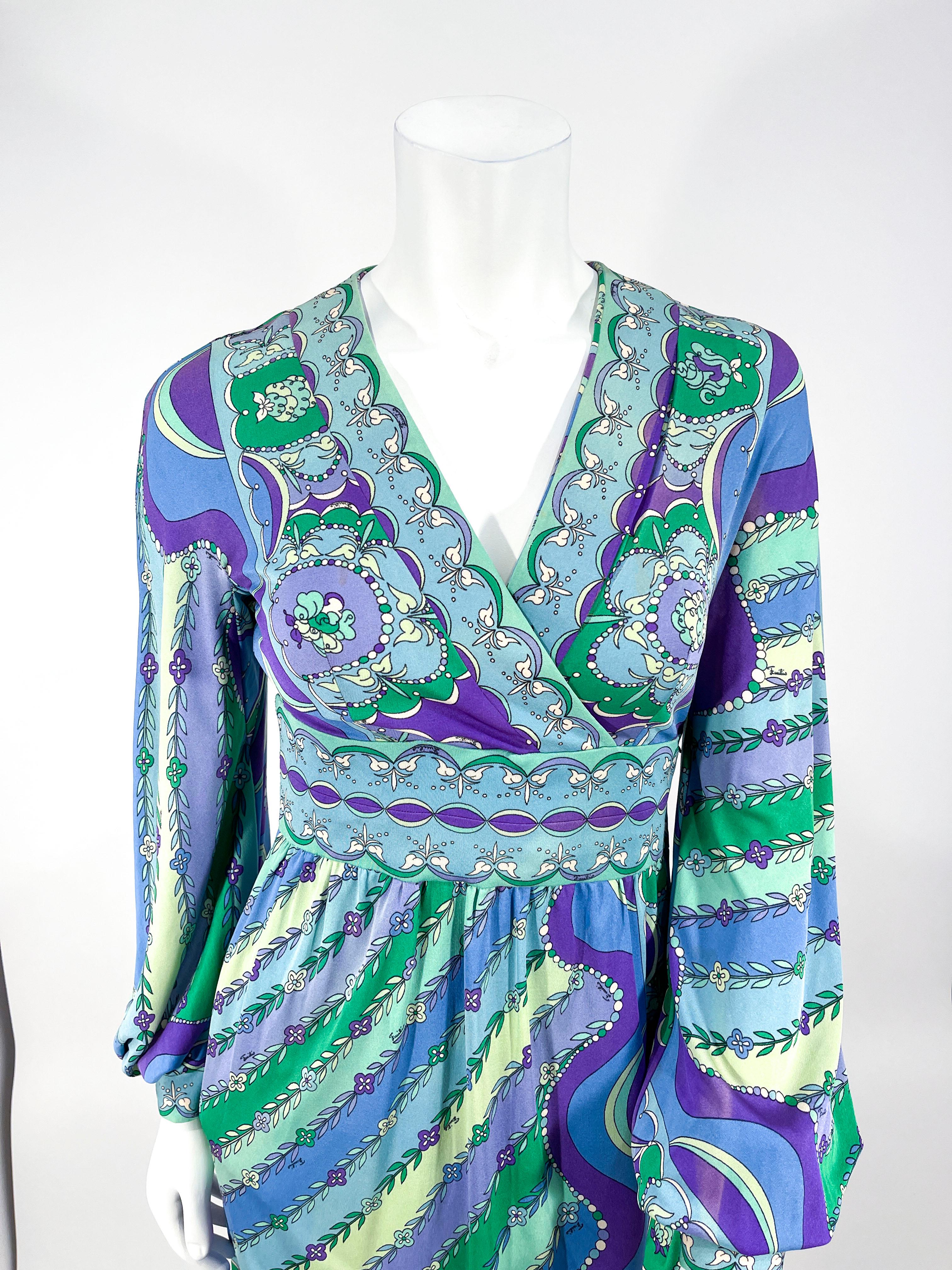 Late 1960s Emilio Pucci Psychedelic printed silk jersey knit dress in jewel tones of blue, teal, purple, green, and white. There are matched boarder prints along the faux wrap bodice, neckline, cuffs and hem. The sleeves have a full bishop