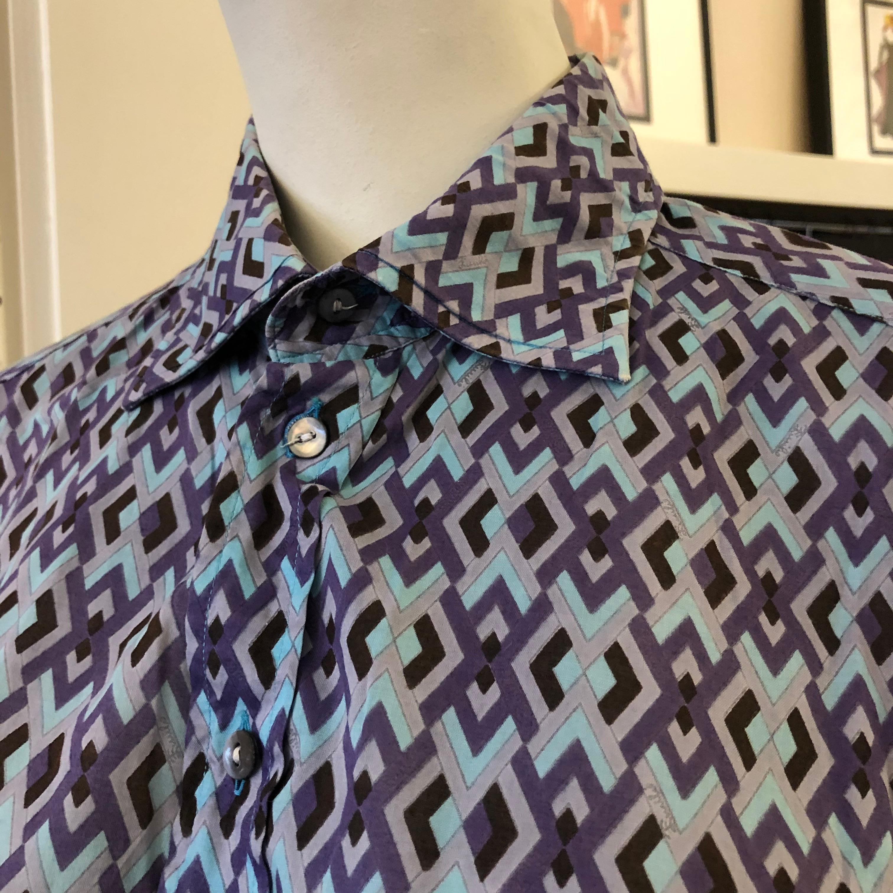 This Emilio Pucci men's shirt has a geometric diamond pattern, reminiscent of the late 60s early 70s. It is of very good vintage condition with side vents, nacre buttons and signed.  The primary colors are aqua and a flight of purples.